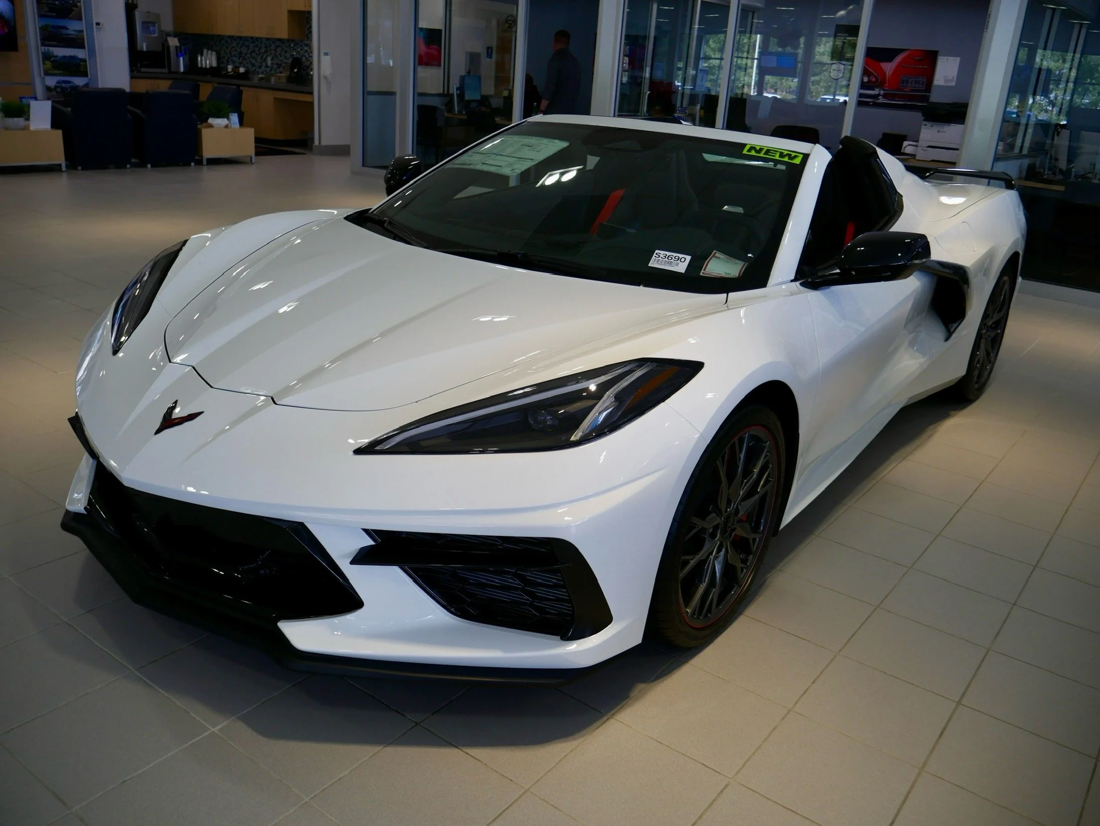 A white Chevrolet Corvette convertible on display in a showroom.
