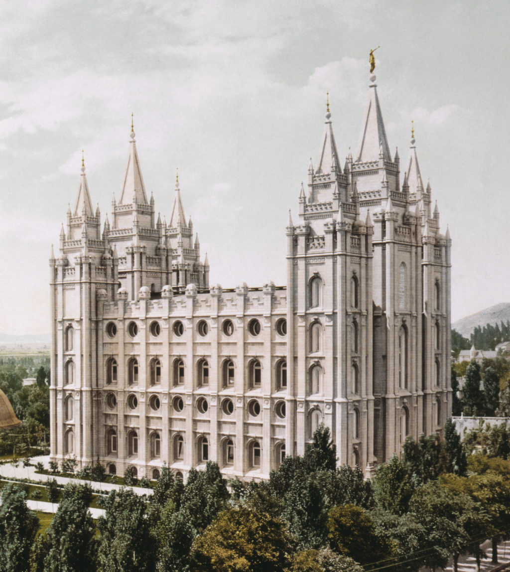 Salt Lake Temple, a large Gothic-style temple with tall spires and detailed stonework, surrounded by trees and mountains under a cloudy sky.
