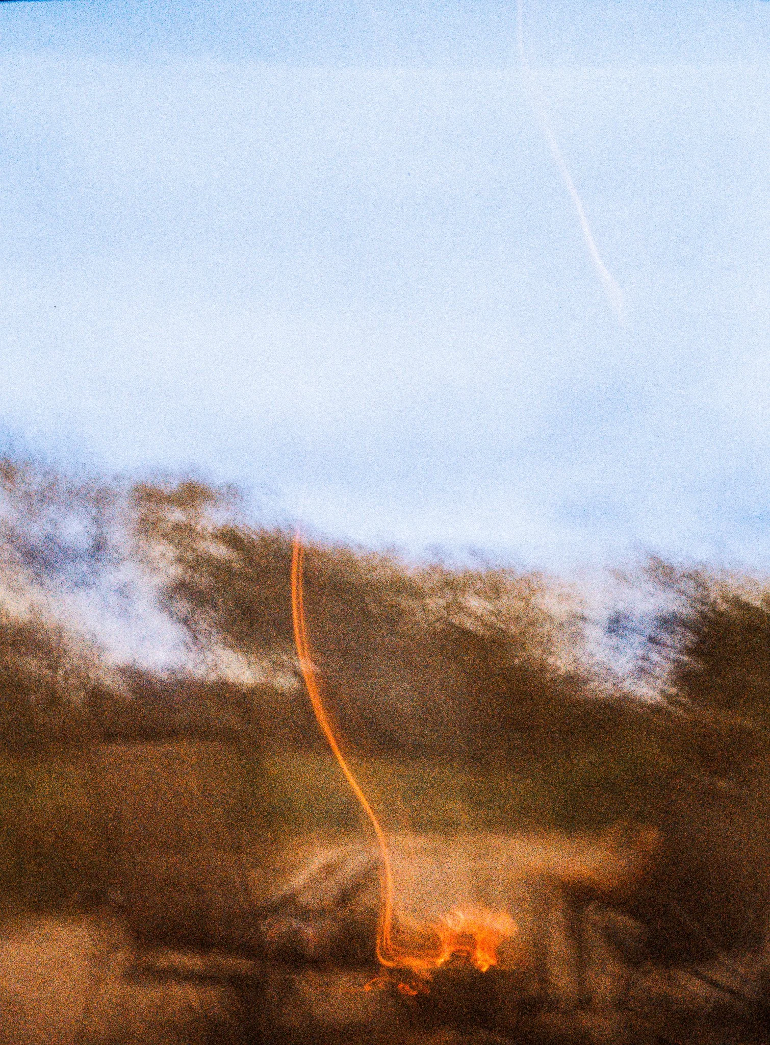 Lightning strike during a storm with dark clouds and a light blue sky.