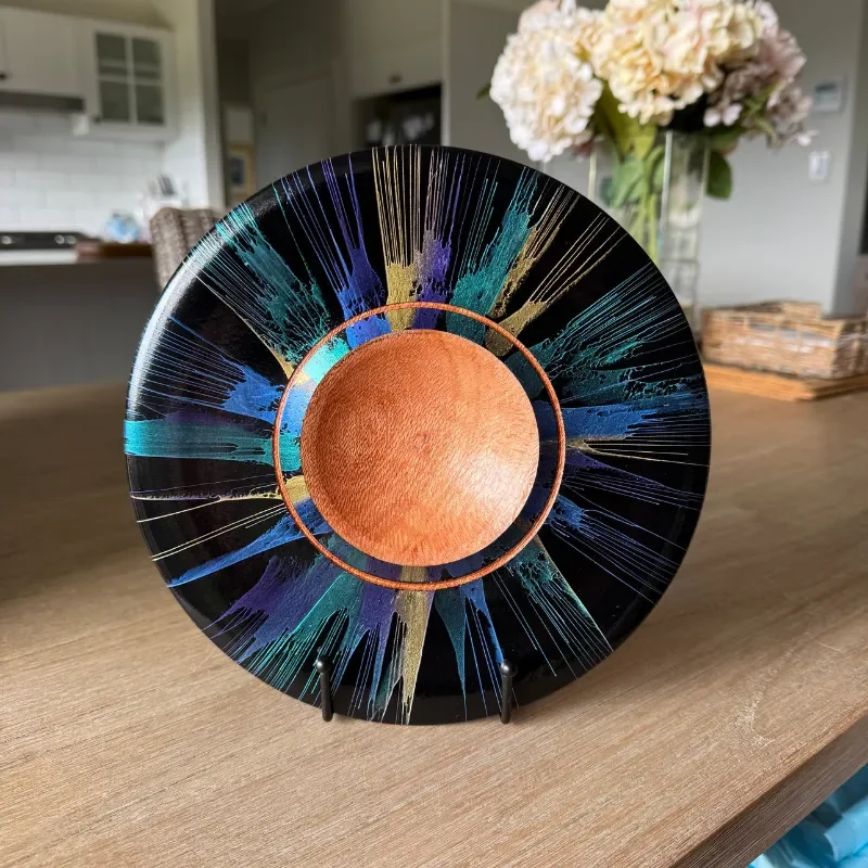 Decorative vinyl record with abstract splatter design in blue, purple, gold, and teal colors, displayed on a wooden surface.