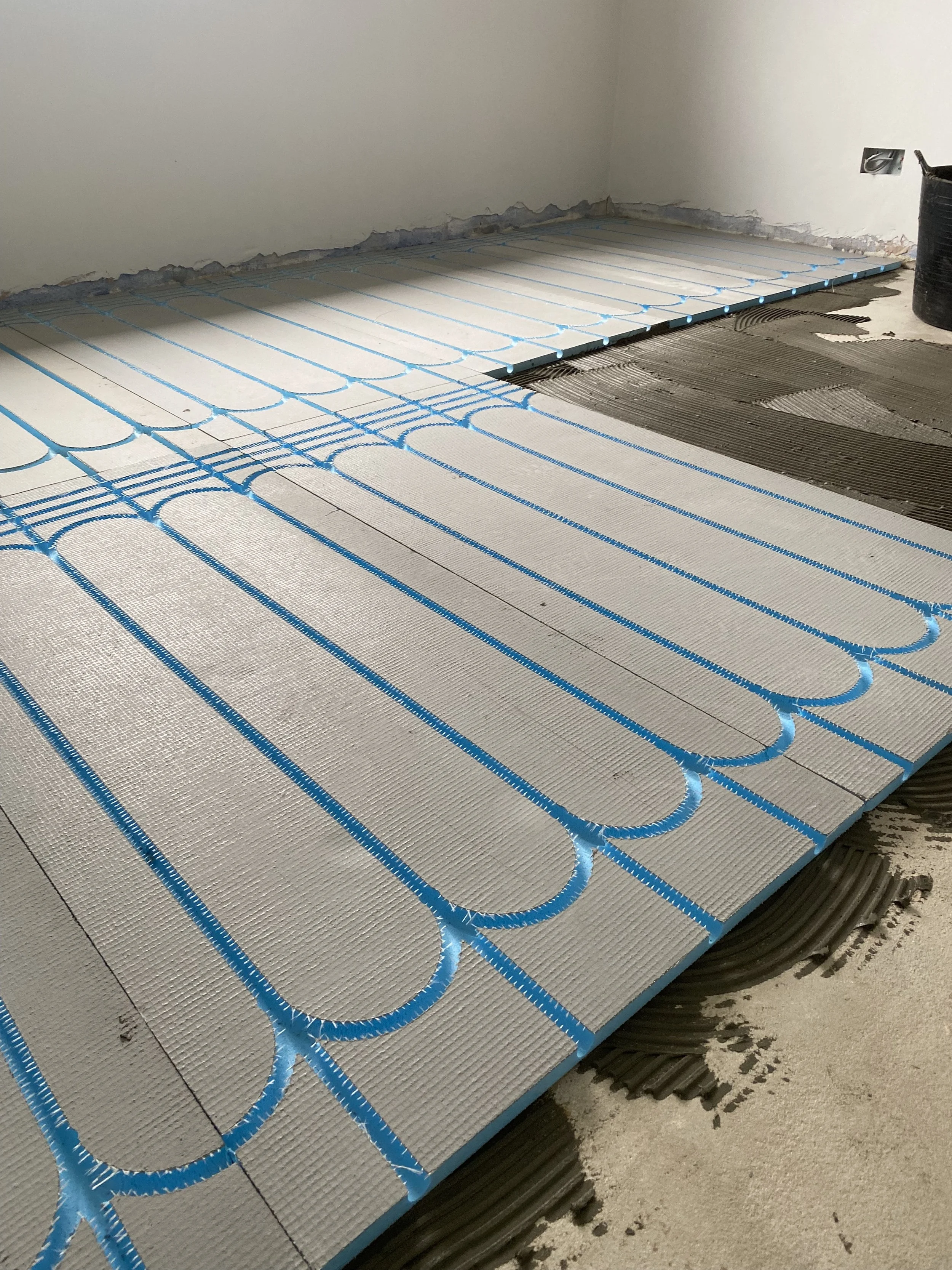 Underfloor heating installation with pipe mats on a subfloor, preparing for floor covering.