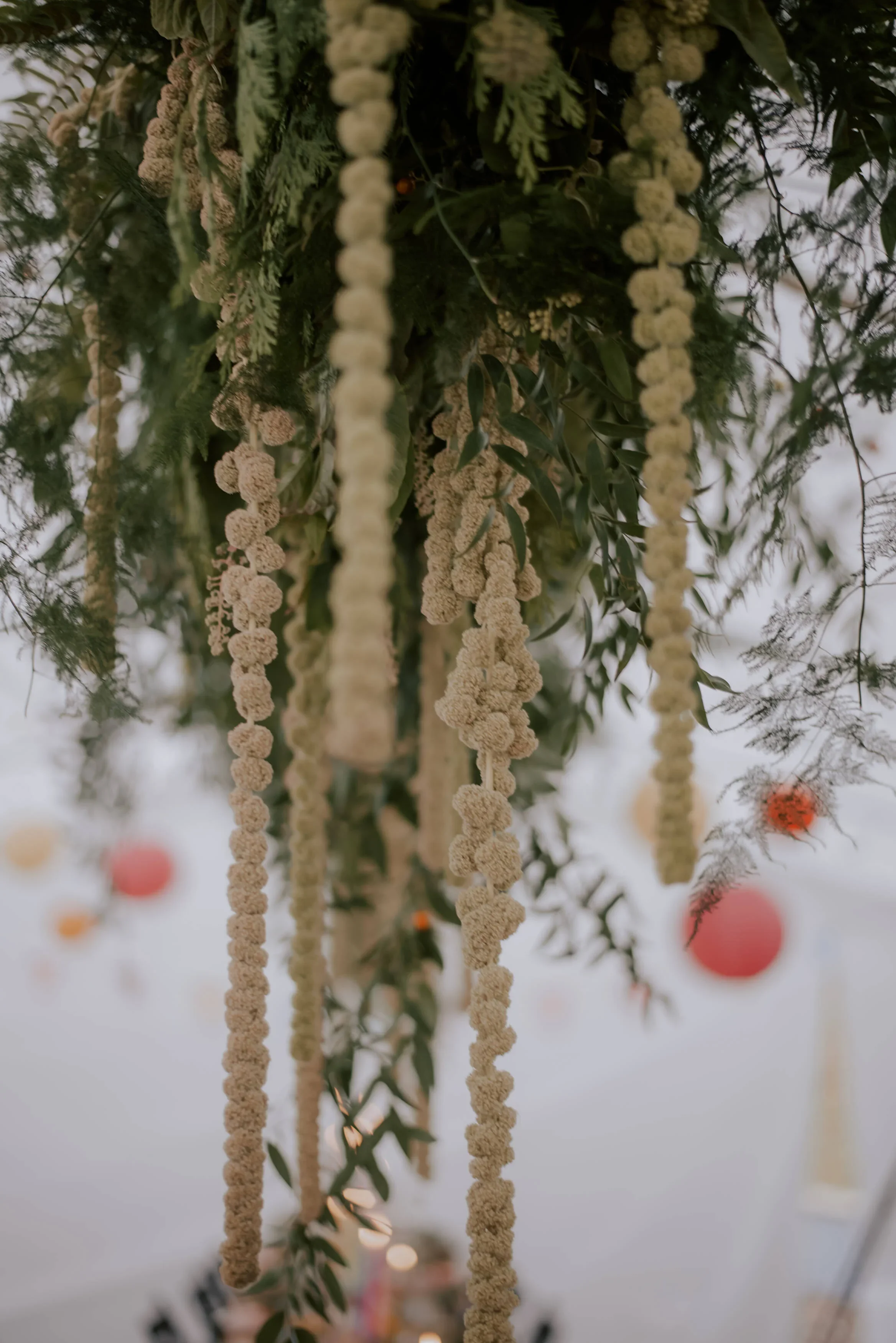 Hanging floral arrangements with white flowers and green foliage, with pink and orange paper lanterns in the background.
