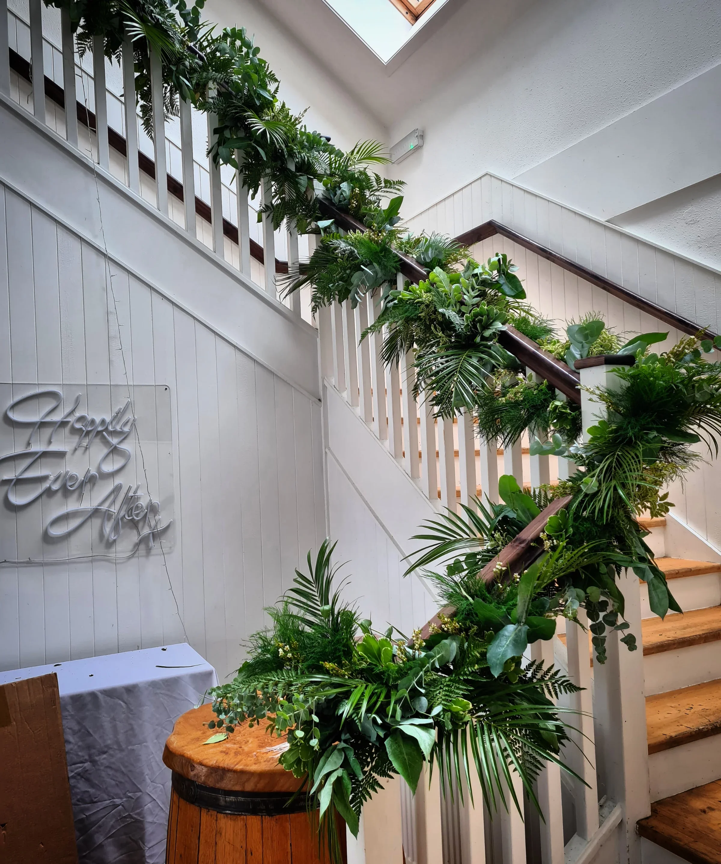 Indoor staircase decorated with lush green plants and foliage, with a skylight above.