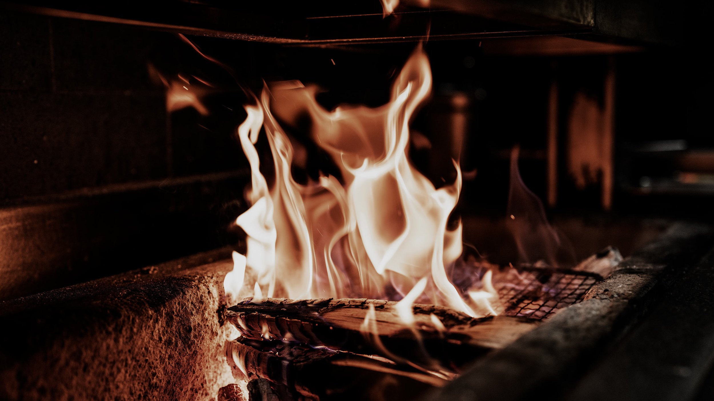 Close-up of wood on a grill or open fire with flames rising and flickering.