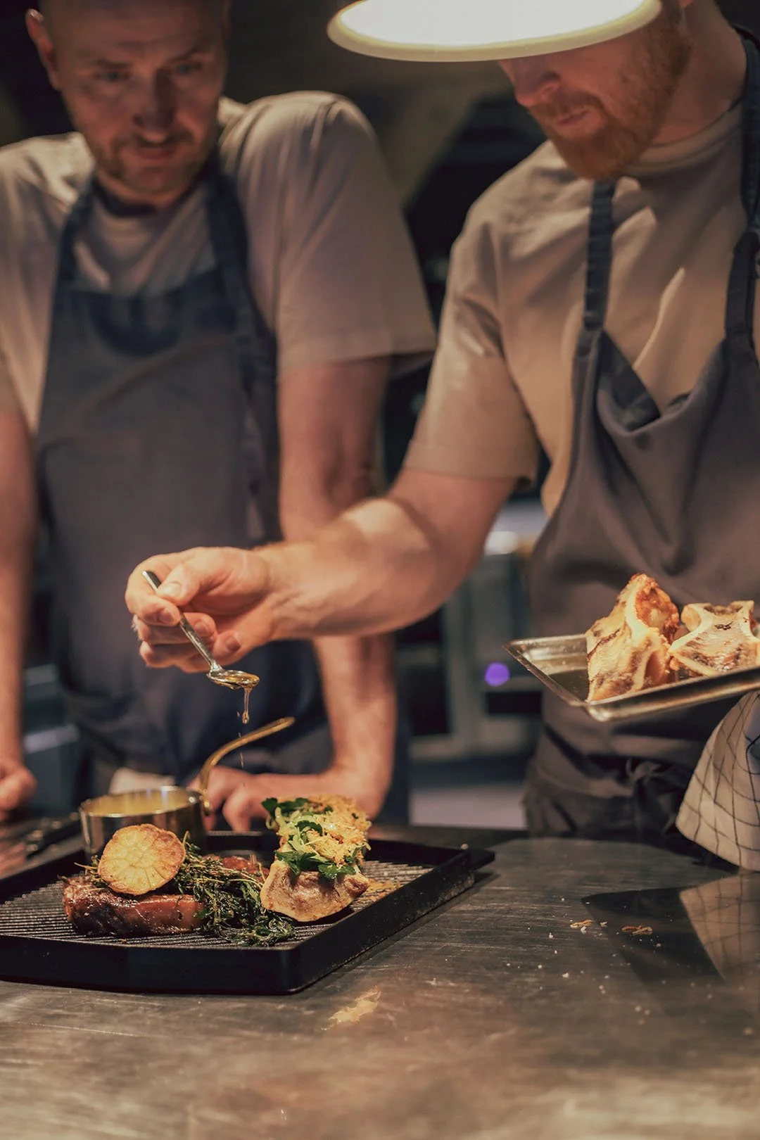 Two chefs preparing a dish of entrecôte with béarnaise sauce