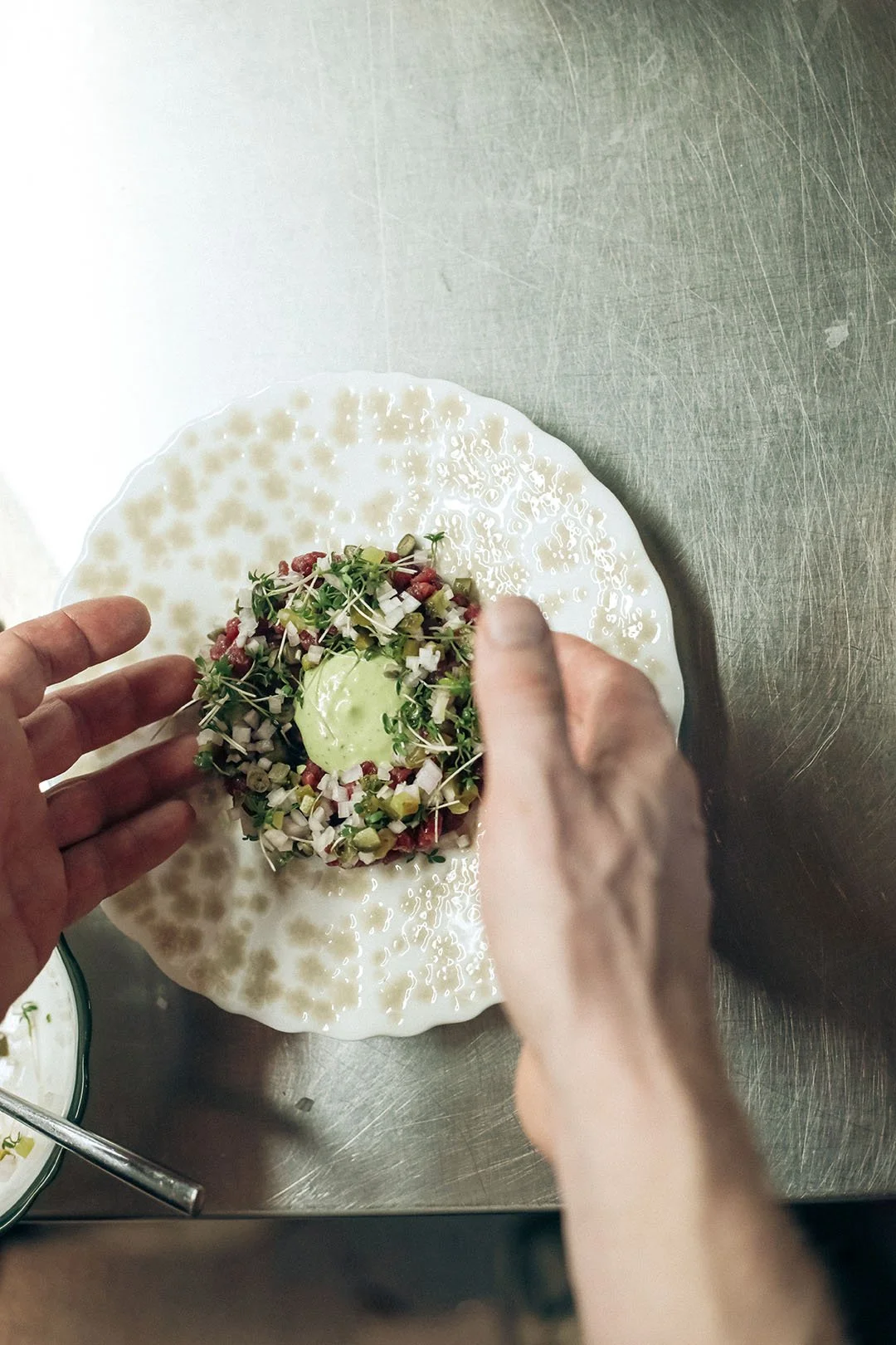 A chef arranging steak tartare on a plate.