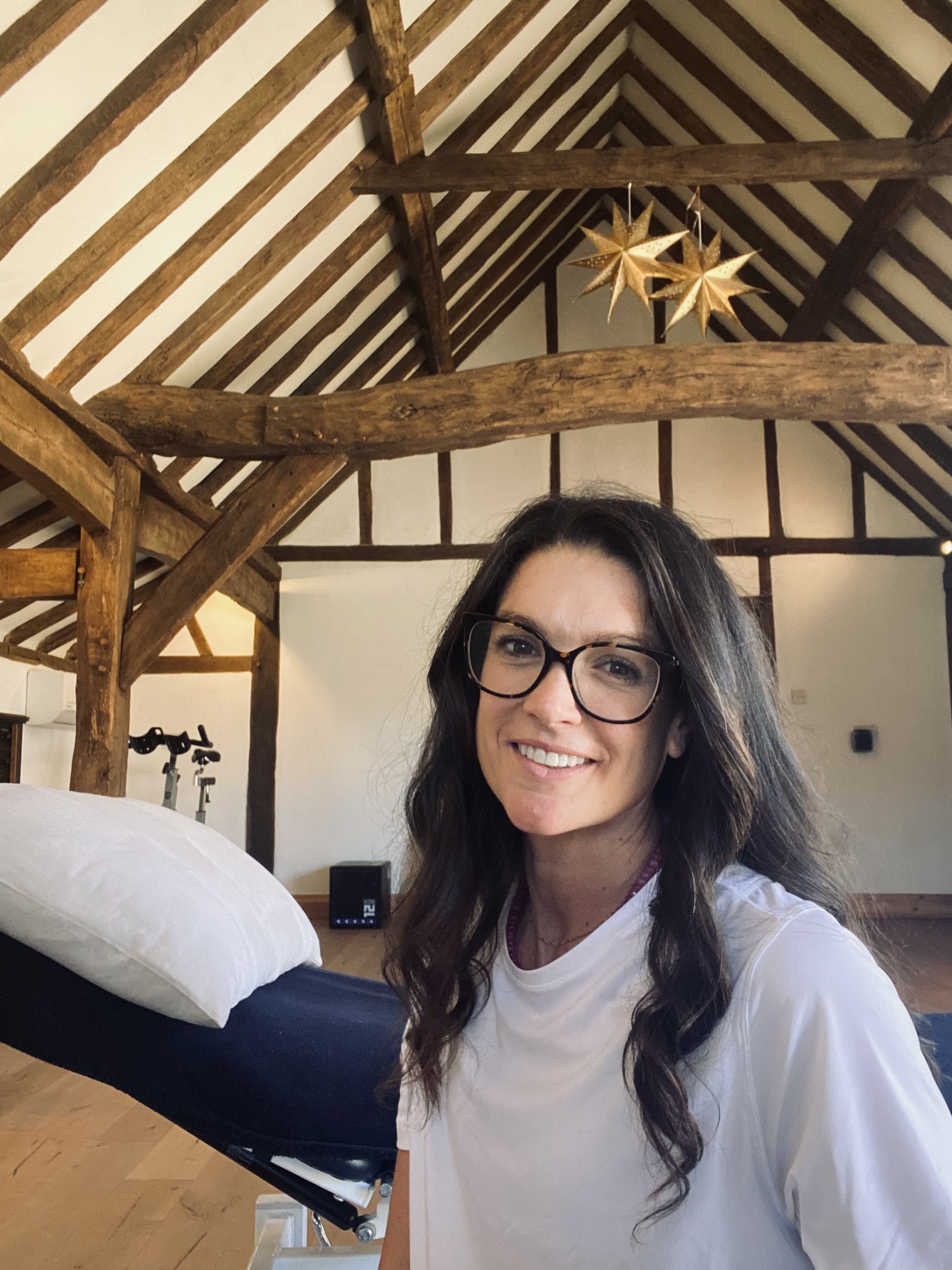 Physiotherapist smiling in a converted barn clinic in Horsely, Surrey
