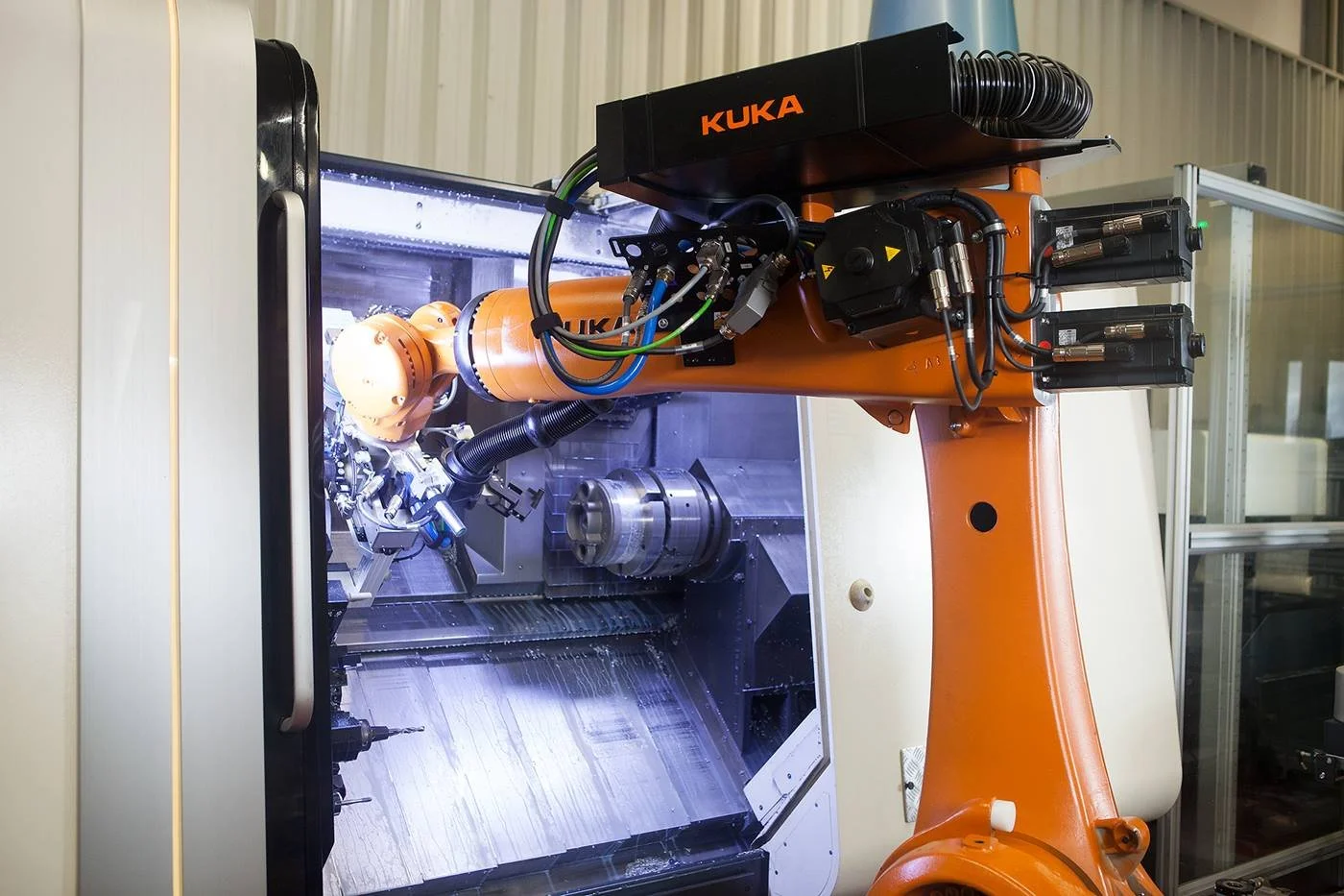 Endüstriyel robot kolu, metal işleme makinesinde çalışıyor.