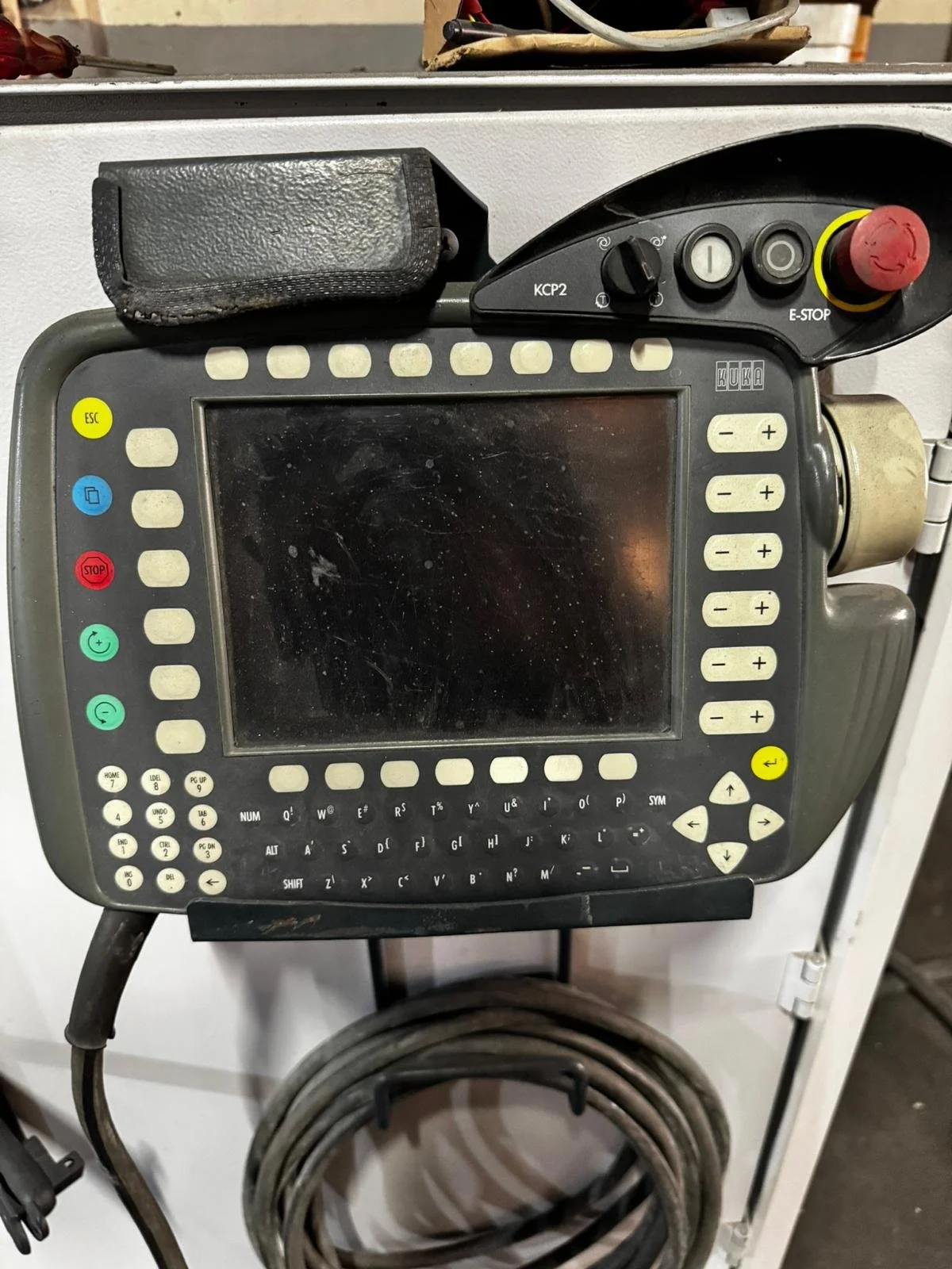 Endüstriyel bir makine kontrol paneli, düğmeler, ekran ve çeşitli kontrol düğmeleri içeriyor.