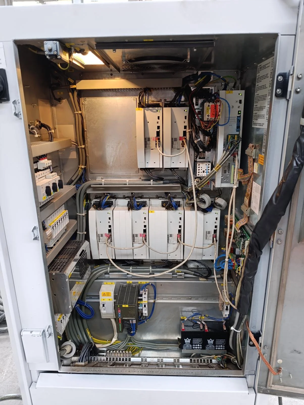 Elektrik panosu içi, çeşitli devre kartları, bağlantı kabloları ve elektrik bileşenleri görünmektedir.