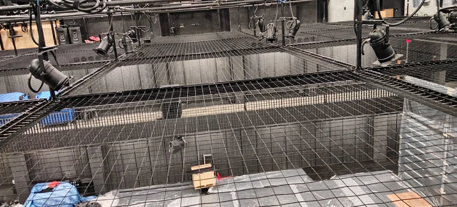 A metal framework of scaffolding with stage lights attached, used for lighting and supporting equipment in a manufacturing or production setting.