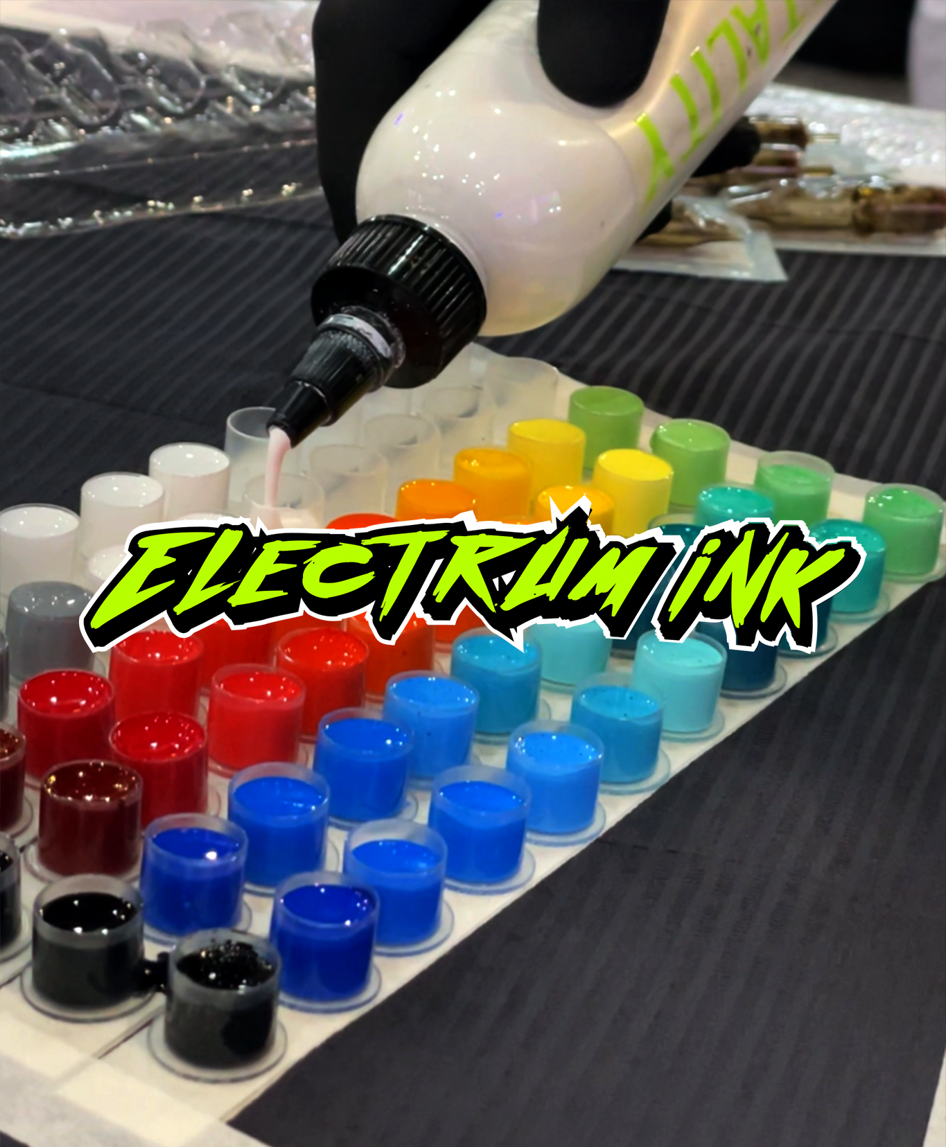 Person wearing black gloves filling small containers with colorful ink or paint from a large bottle labeled 'FARAH' on a table.