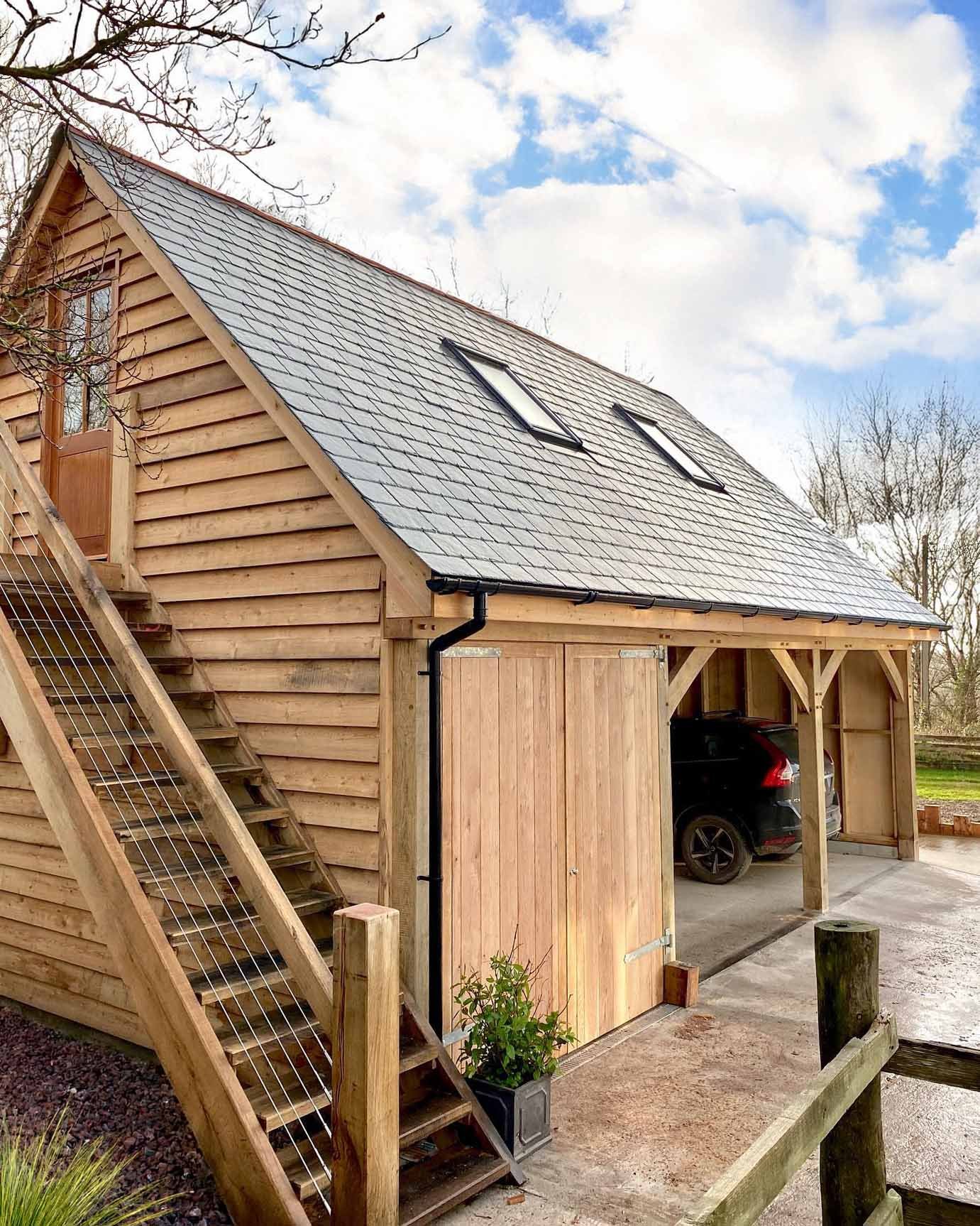 Oak Frame Two story garage with living accommodation above. External steps lead to accommodation, below is a enclosed garage space and a two vehicle car port