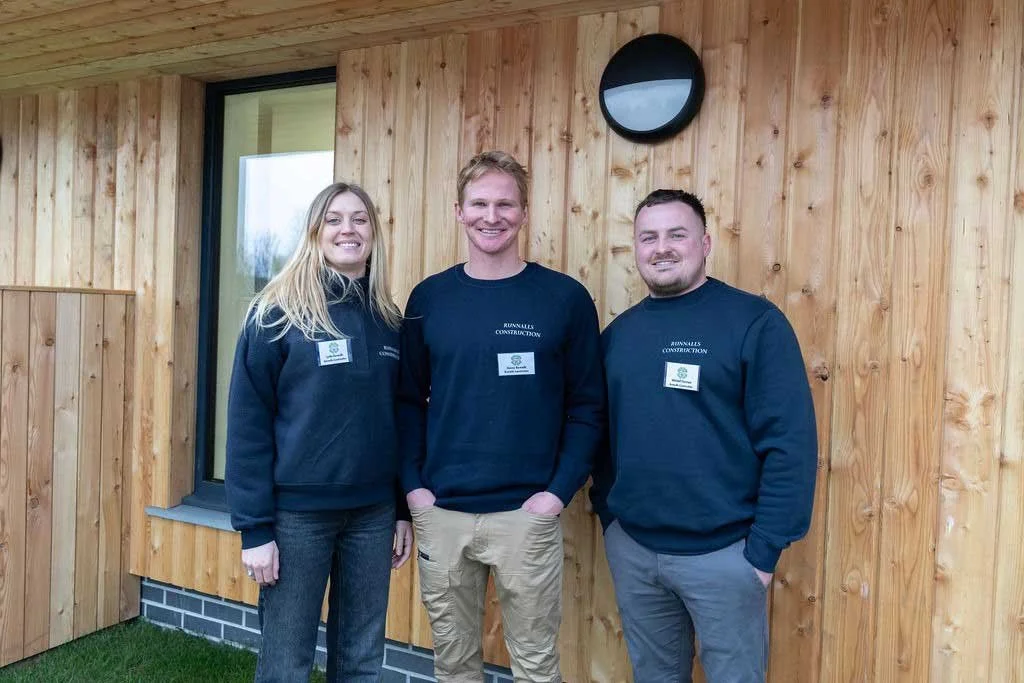 Lydia, Danny and Mitchell, some of the team from Runnalls Construction outside the St Tudy community center in Cornwall in their Runnalls Construction Jumpers
