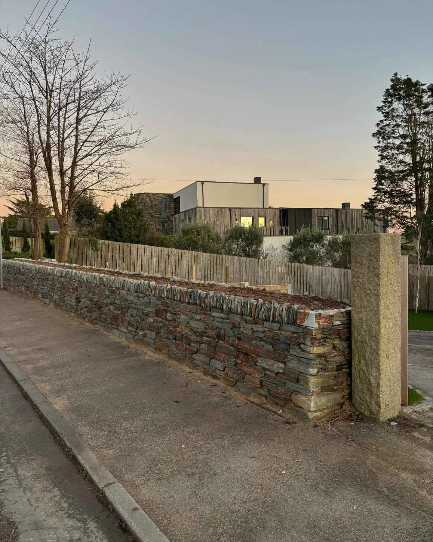 A stone and brick retaining wall along a pavement creating a stunning boundary for a modern home. Part of a landscaping project in Rock, Cornwall