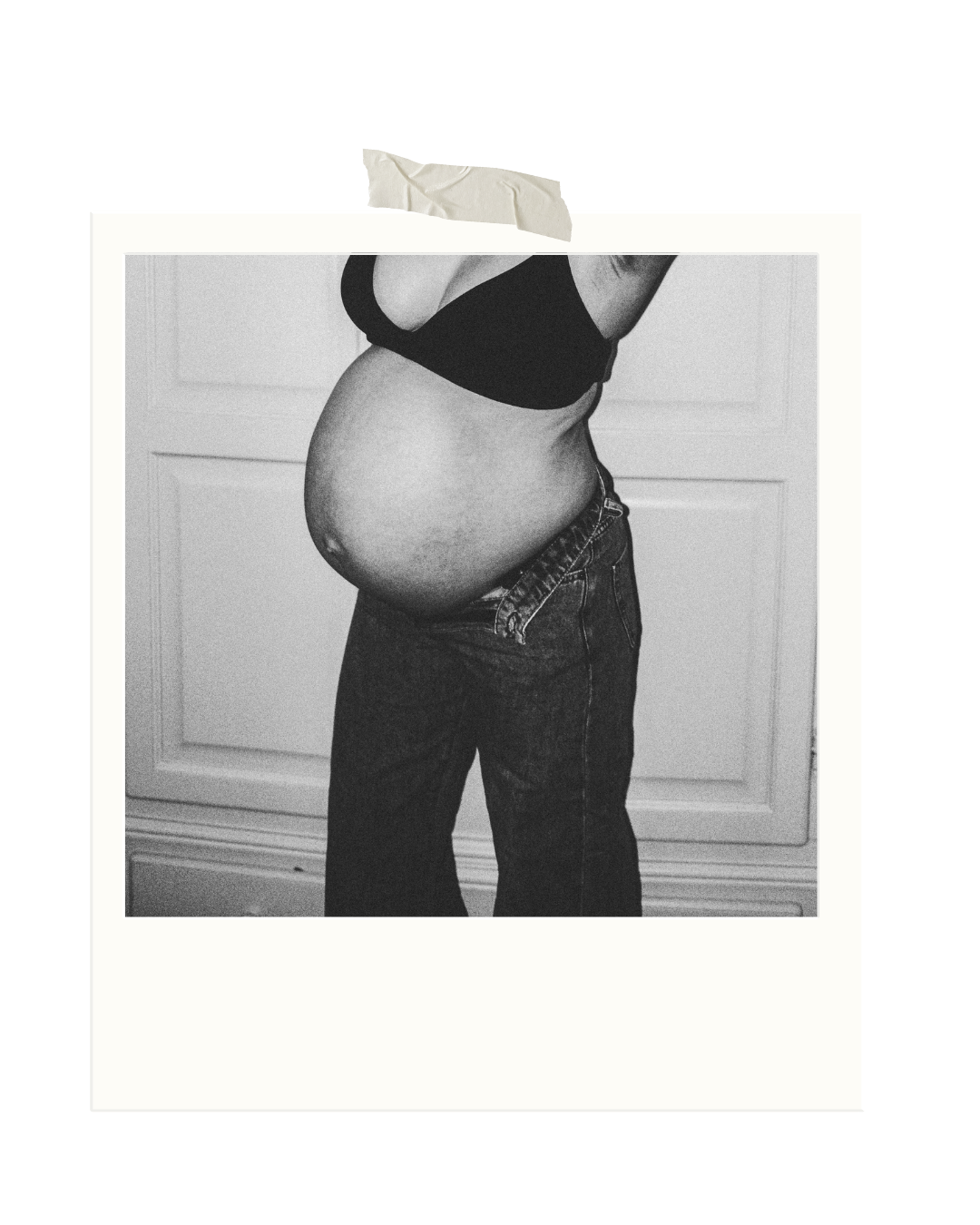 Schwarz-weiß-Porträt einer schwangeren Frau in Jeans – ein ruhiges, künstlerisches Bild über Körper, Veränderung und werdende Mutterschaft. Der Hintergrund ist eine Vintage Kleiderschrank.