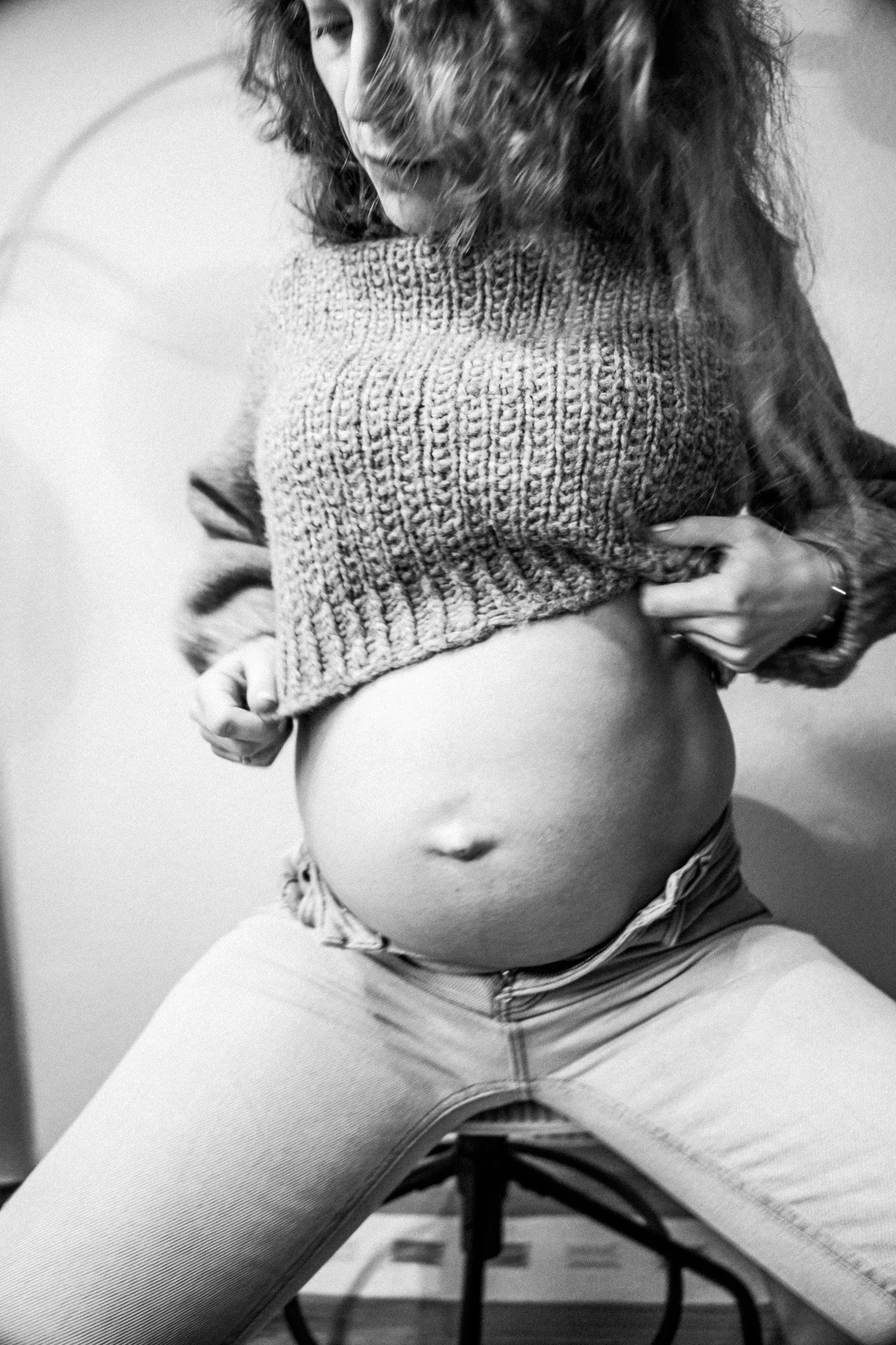 Schwarz-weiß-Porträt einer schwangeren Frau, die ihren Babybauch zeigt – ein künstlerisches Bild über Körper, Veränderung und Mutterschaft.