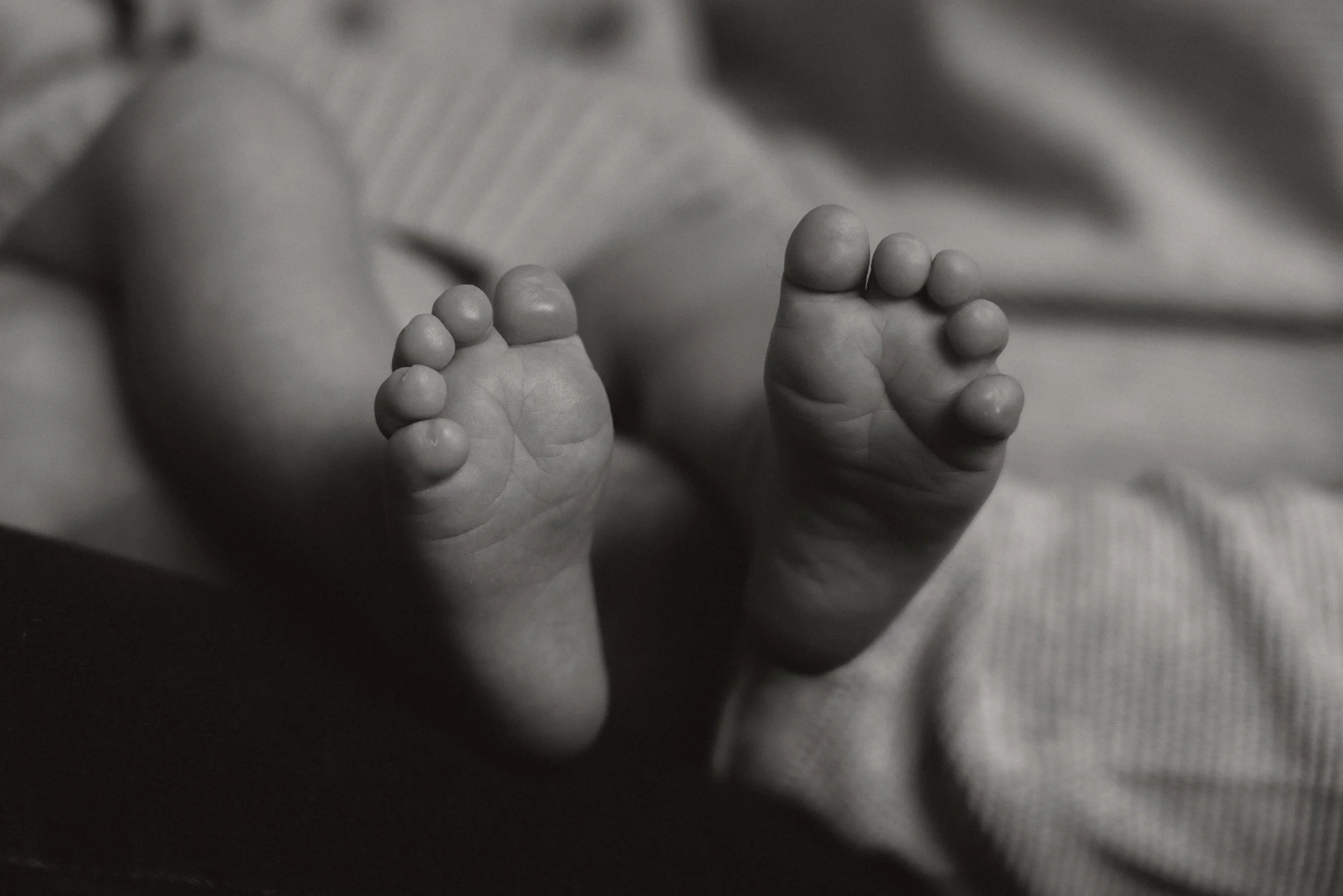 Nahaufnahme von winzigen Babyfüßen in Schwarz-Weiß.