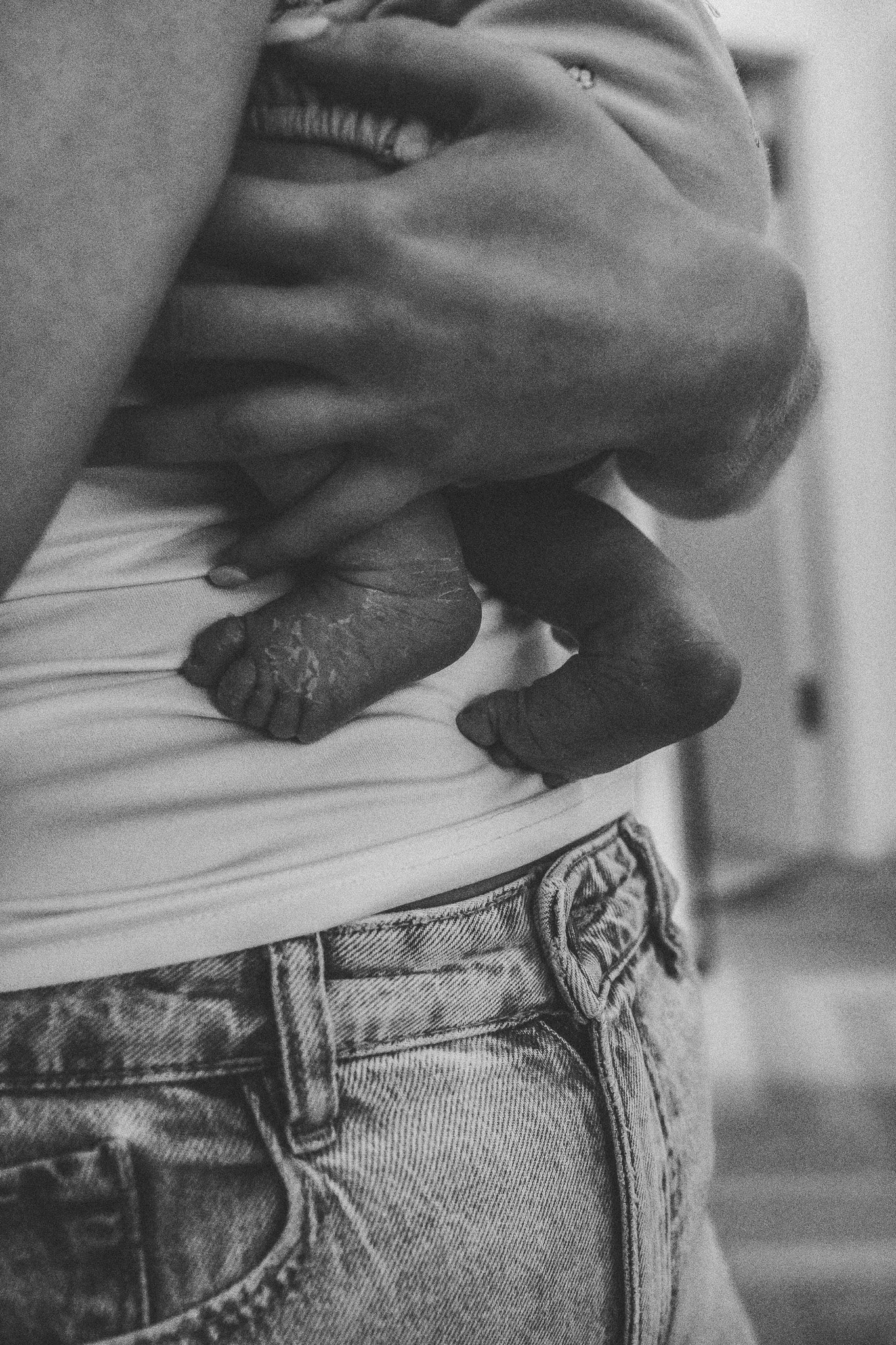 Schwarz-weiß-Detailaufnahme eines Babybauchs über einer Jeans – ein künstlerisches Schwangerschaftsporträt über Körper und Veränderung.