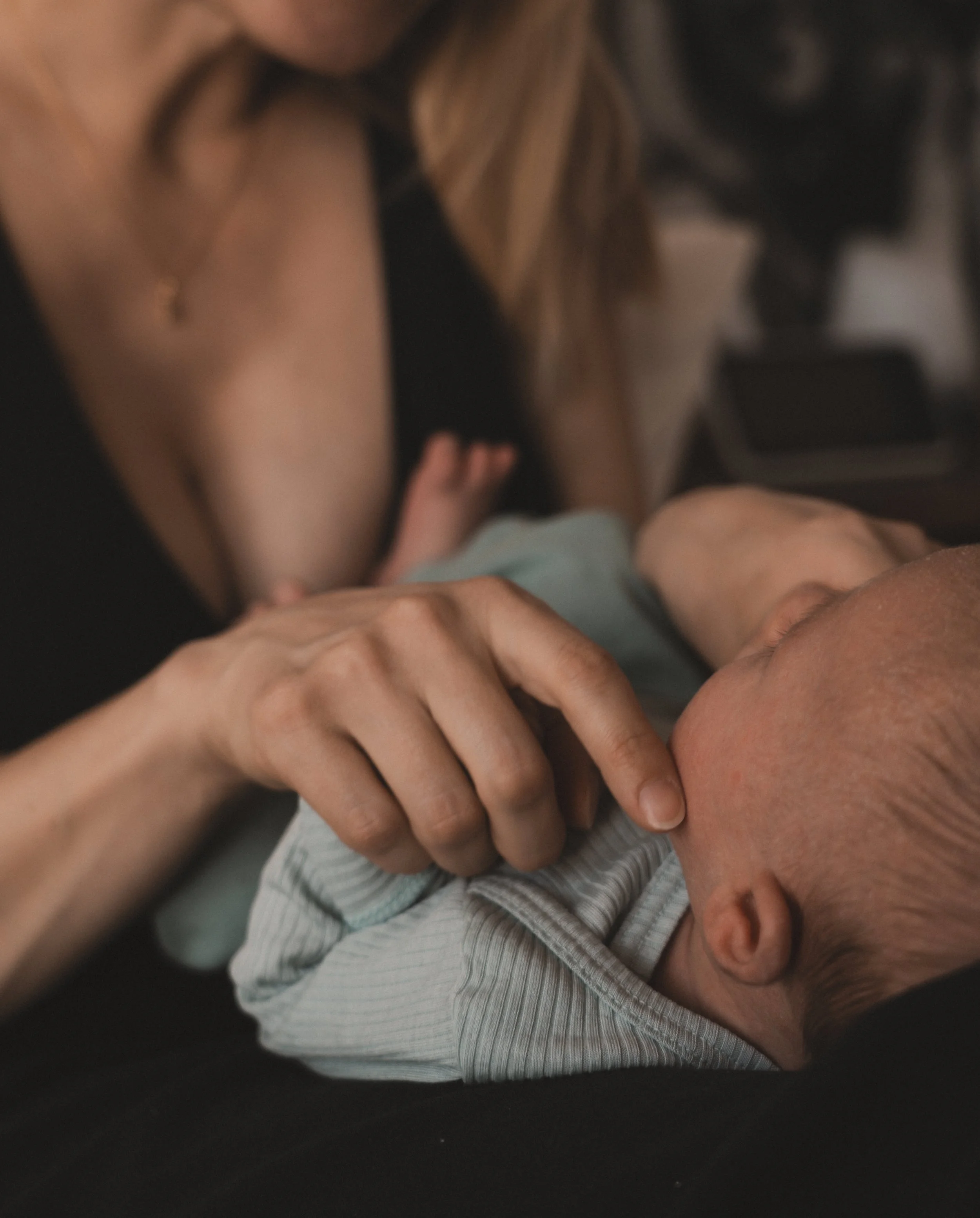 Eine Frau hält ein Baby im Arm, das an ihrer Brust saugt, während sie liegt.