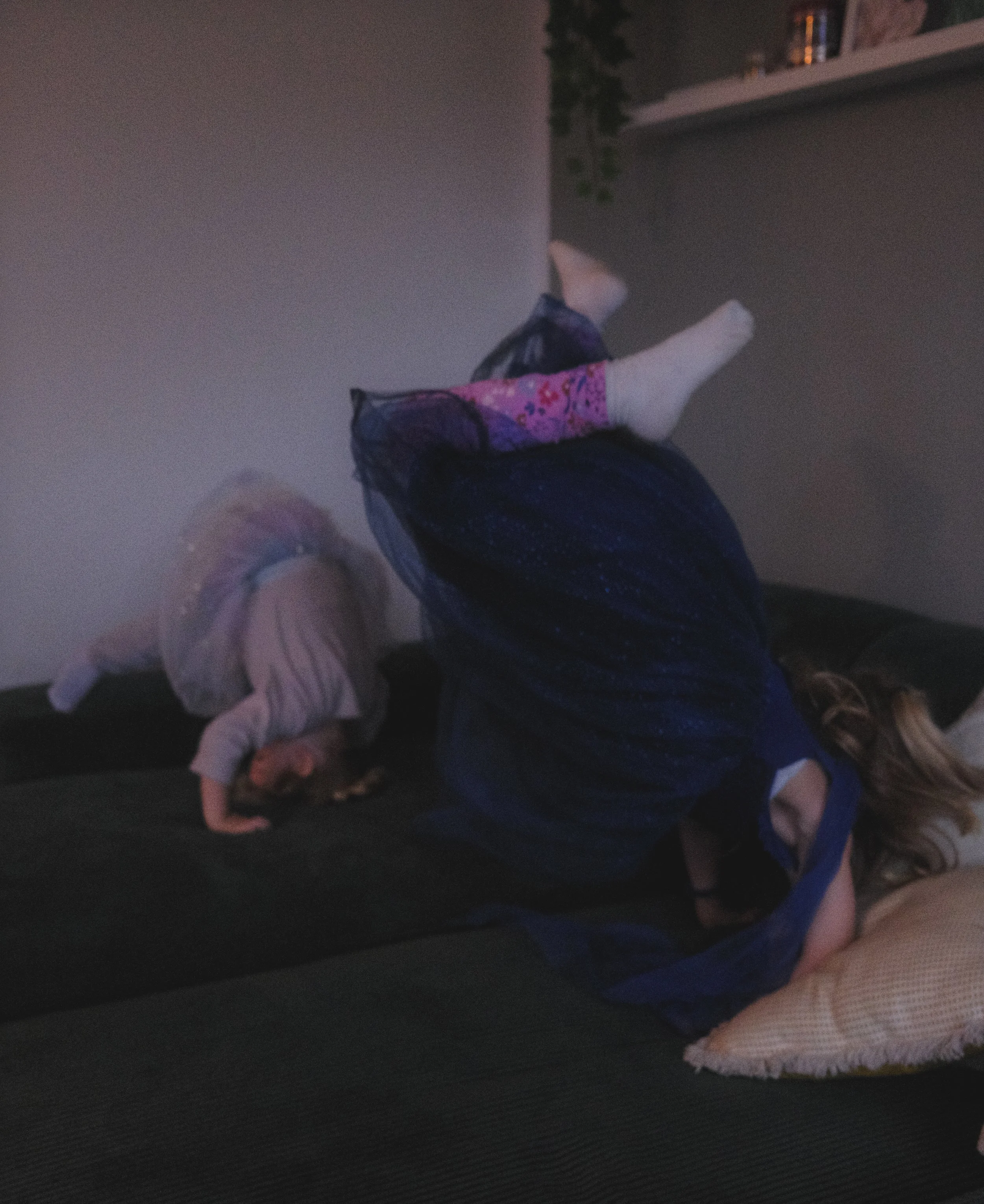 Zwei Kinder toben und kuscheln auf einem Sofa – lebendige Familienfotografie voller Nähe und Bewegung.