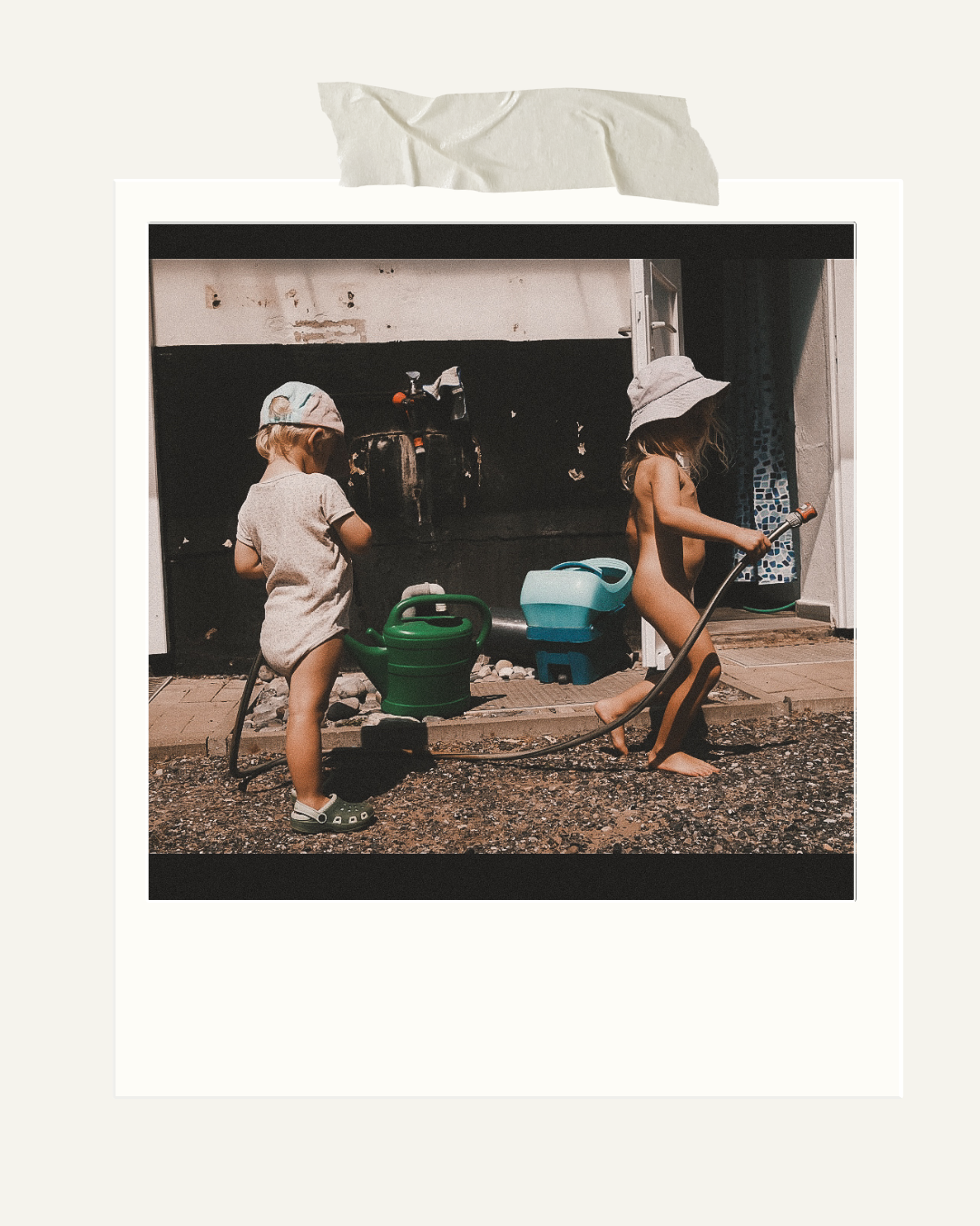 Zwei kleine Kinder spielen im Sommer mit Wasser vor ihrem Zuhause – ein fröhlicher Moment aus dem Familienalltag. 