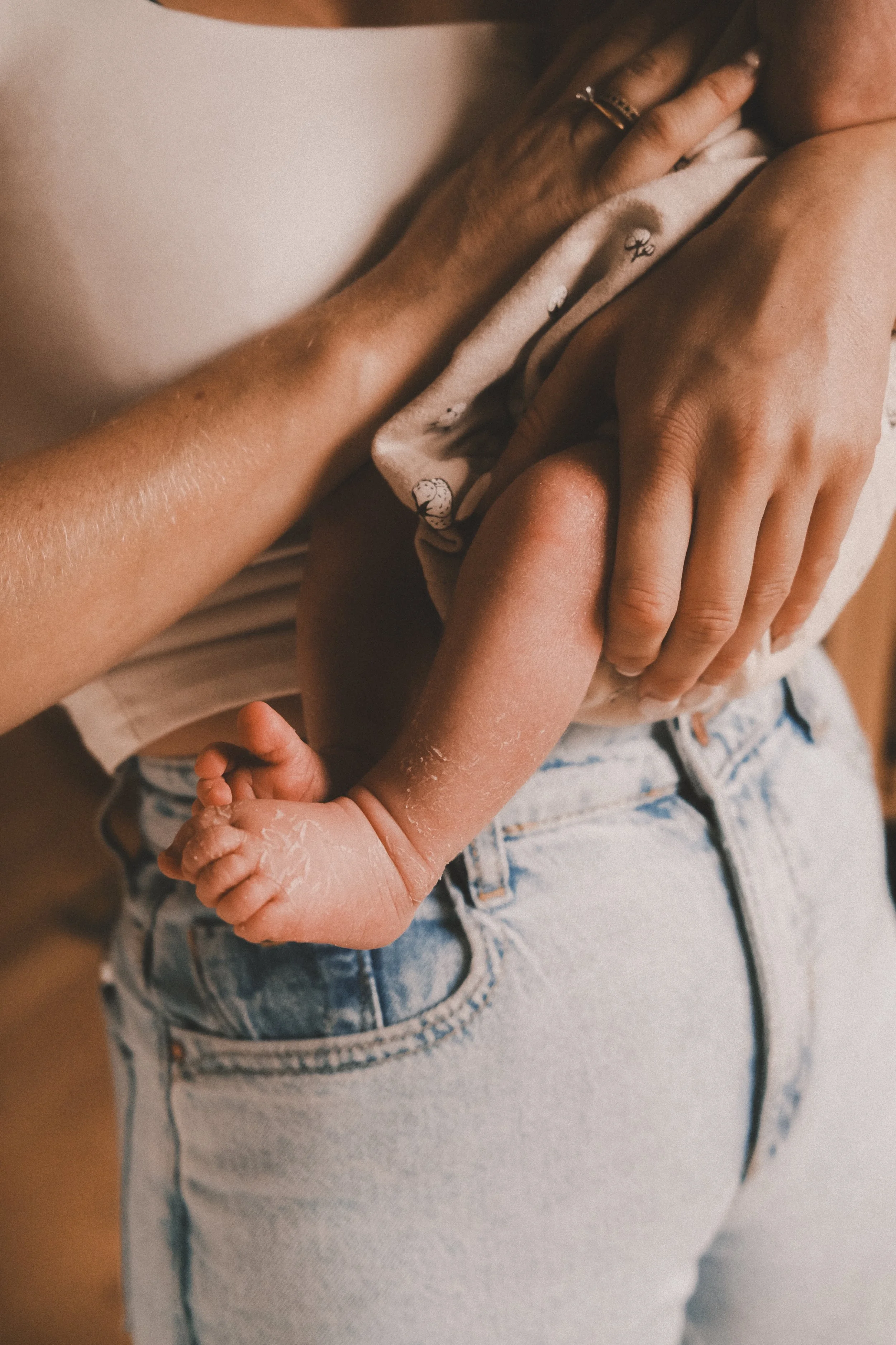 Ein Neugeborenes liegt in den Armen seiner Mutter – ein nahes, zärtliches Porträt aus einer Wochenbett-Fotostory.
