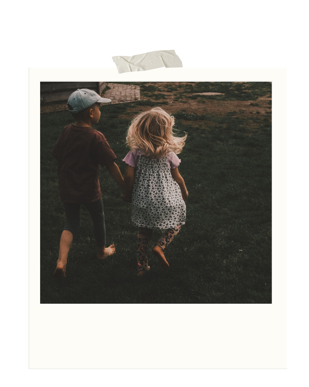 Zwei Kinder, ein Junge und ein Mädchen, laufen Hand in Hand durch das Gras, mit einem dunklen Himmel im Hintergrund.