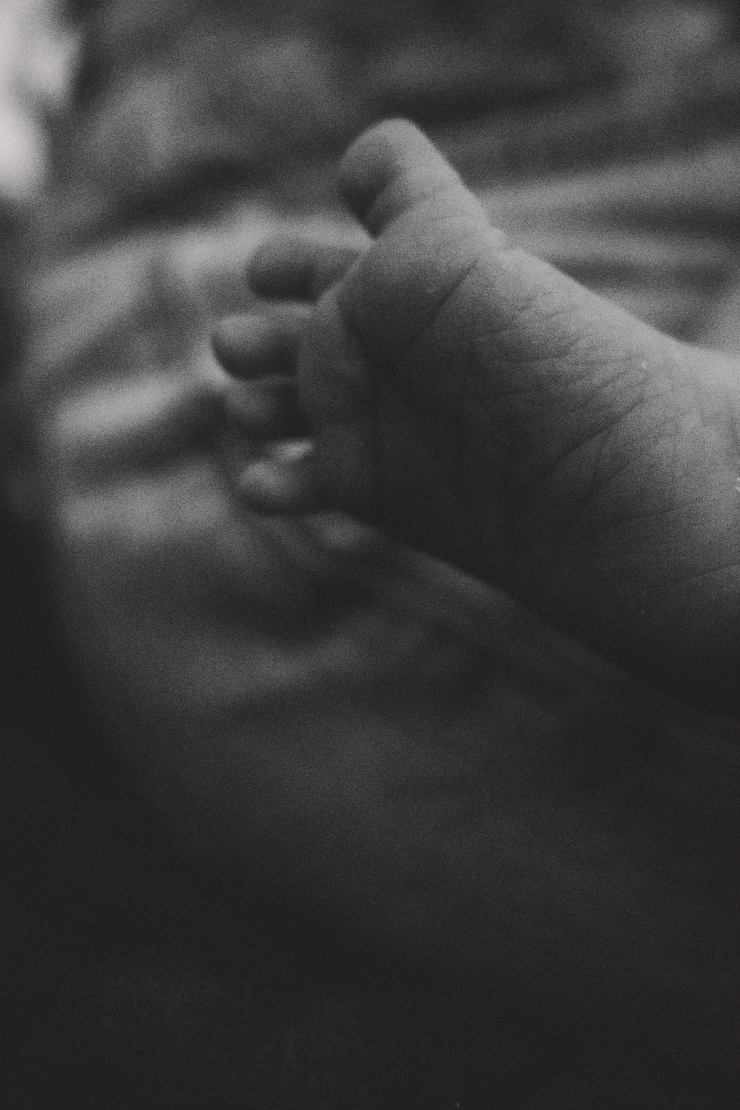 Nahaufnahme eines Babys, das eine Hand hält, in Schwarz-Weiß