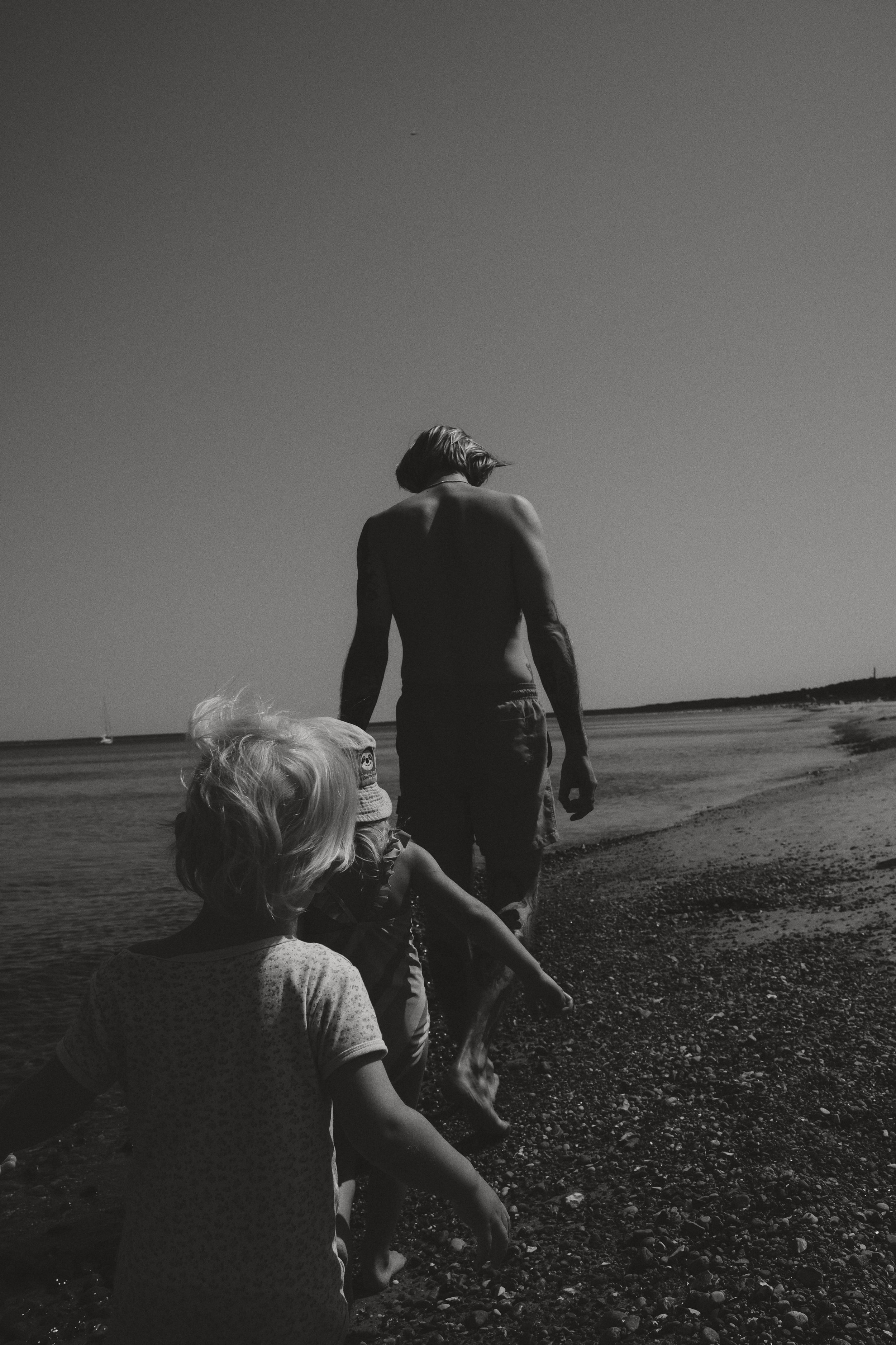 Ein Vater läuft mit seinen Kindern am Strand entlang – eine Schwarz-weiß-Fotografie über Familie, Bewegung und gemeinsame Zeit