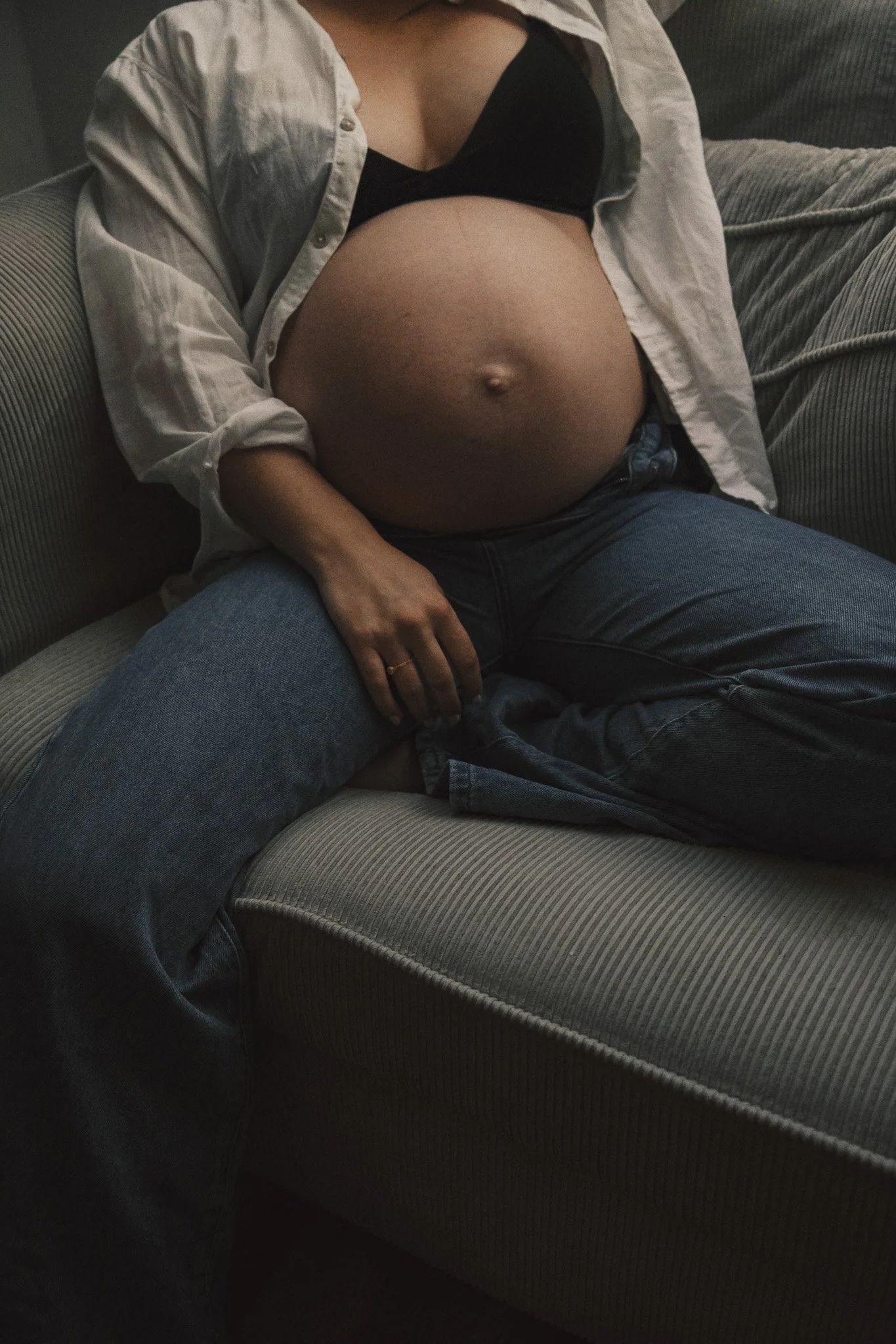 Eine schwangere Frau sitzt entspannt auf einem Sofa im Prenzlauer Berg in ihrer Altbauwohnung – ein natürliches Porträt über Schwangerschaft, Ruhe und Vorfreude.