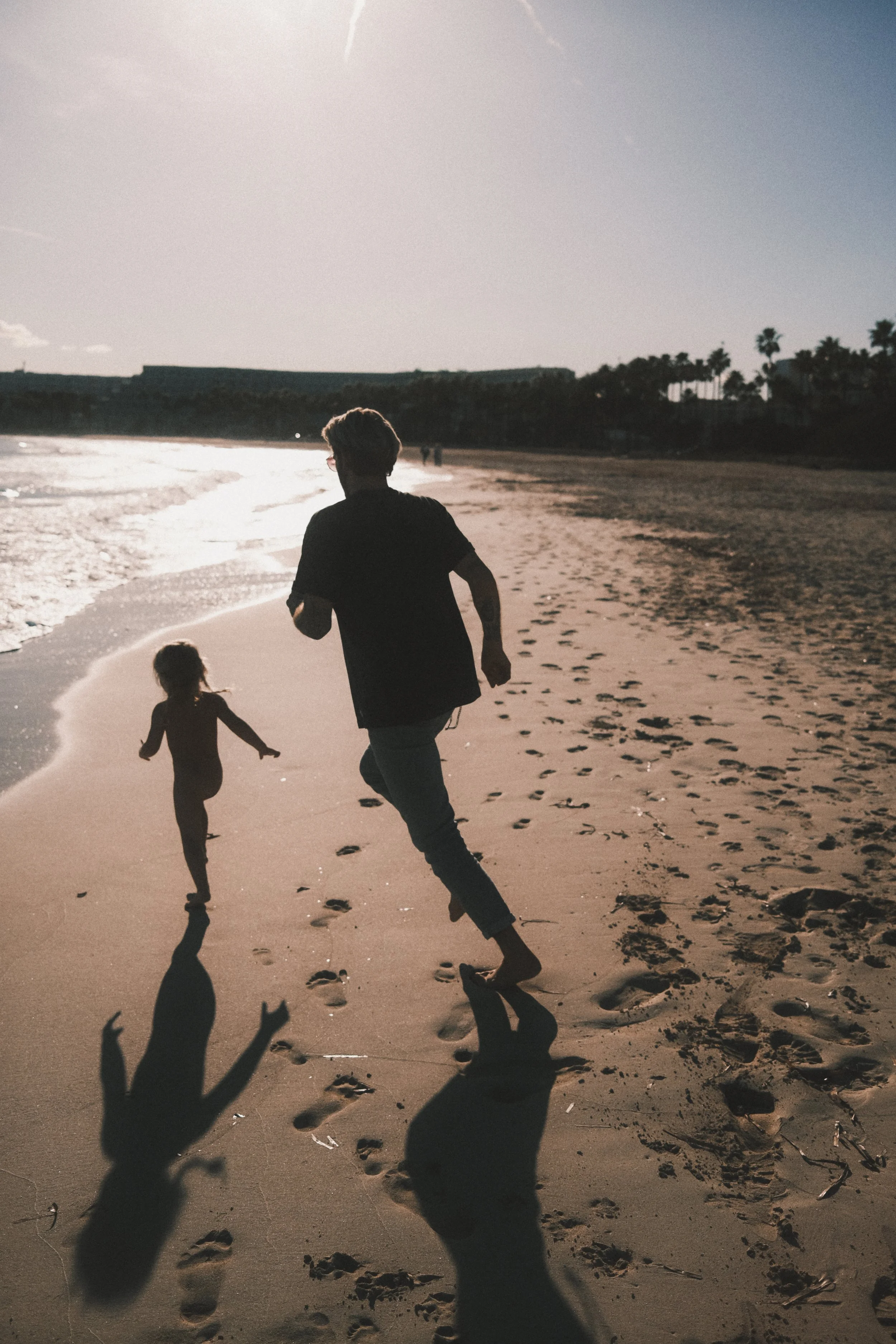 Stimmungsvolles Vater-Kind-Shooting im Gegenlicht am Strand – lebendige Familienmomente im analogen Dark & Moody Stil. Mallorca