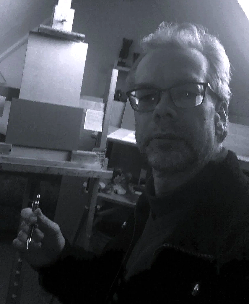 Een kunstenaar, Sietse Jonker, in zijn atelier met schilderezel, daglicht en een tekenpen in zijn hand.