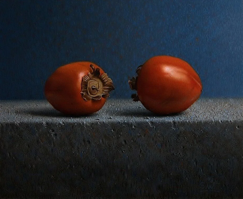 Twee kaki vruchten op een donkere ondergrond, met een blauwe achtergrond