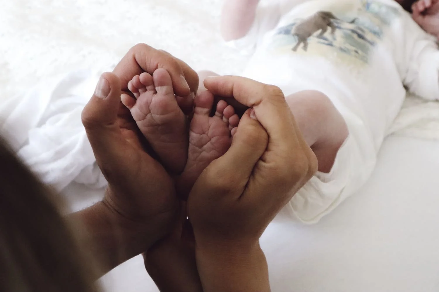Babyfüße eines Neugeborenen die in zwei Händen gehalten werden