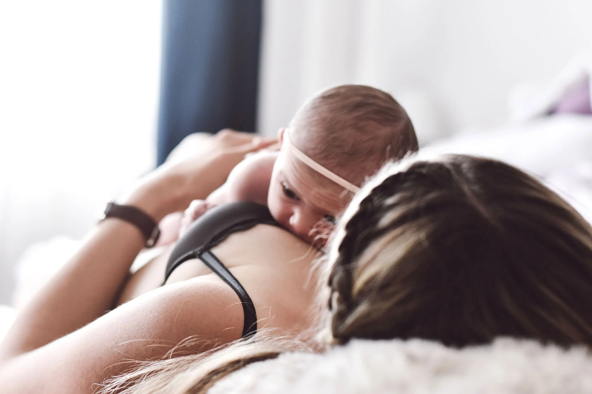 Mutter liegt mit ihrem Baby beim Stillen im Bett