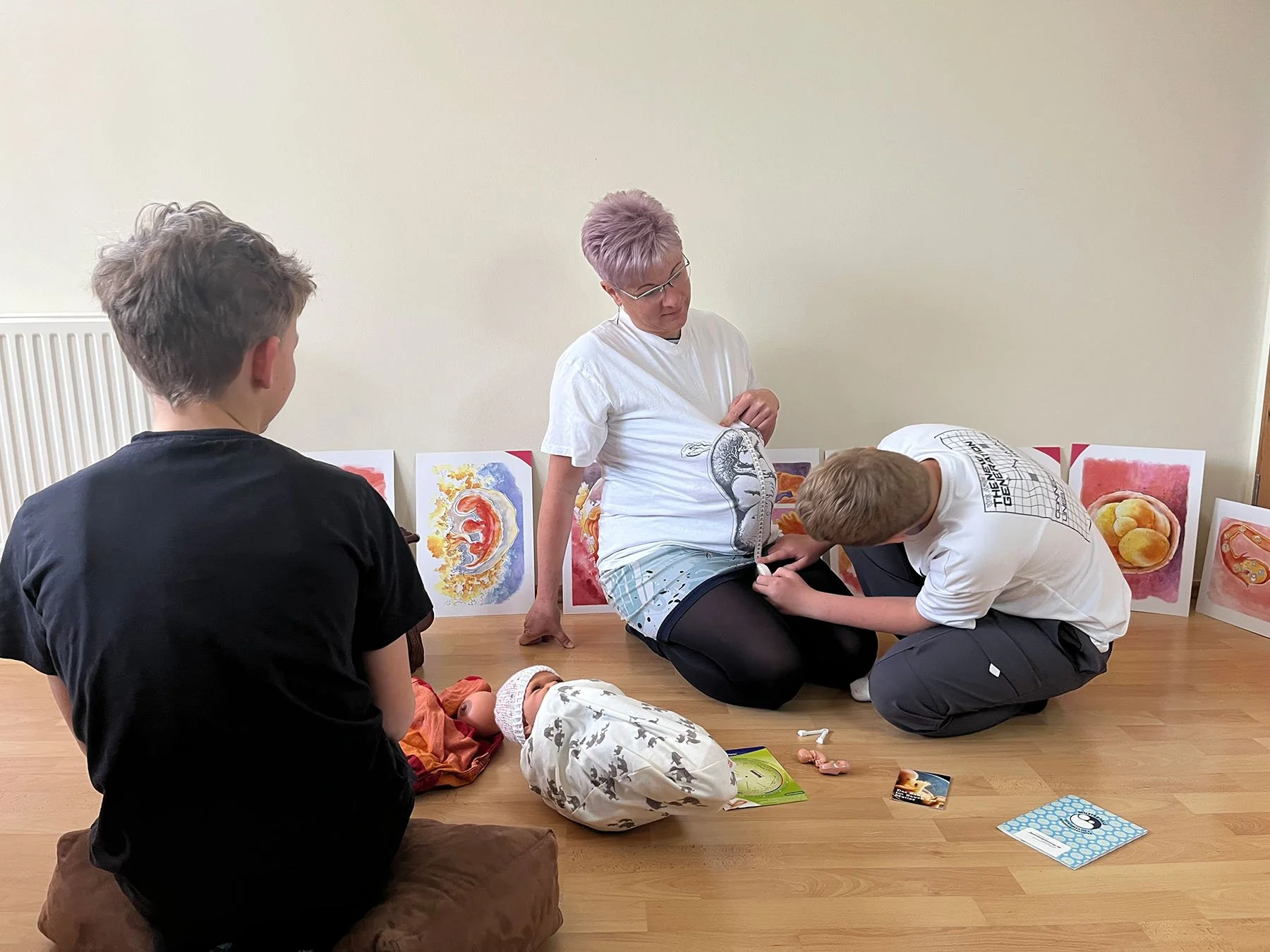 Junge misst den Bauchumfang einer gespielten Schwangerschaft bei einer Hebamme