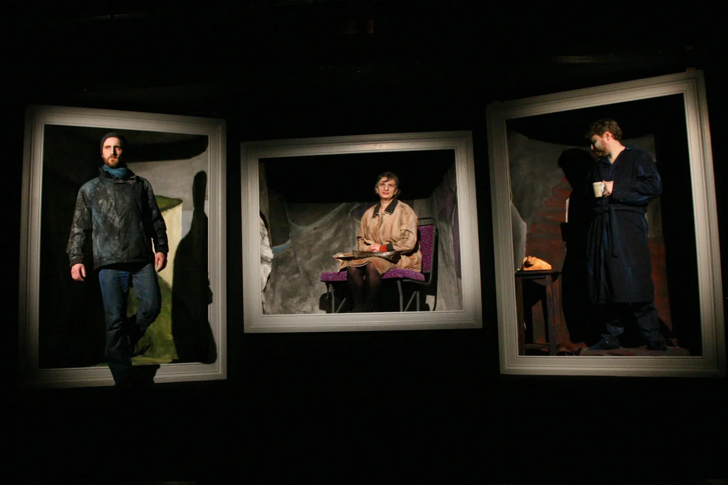 Three framed theatrical scenes featuring actors in different poses and settings, with the middle scene showing a woman seated with a book, and the other two scenes showing men standing, one holding a mug.