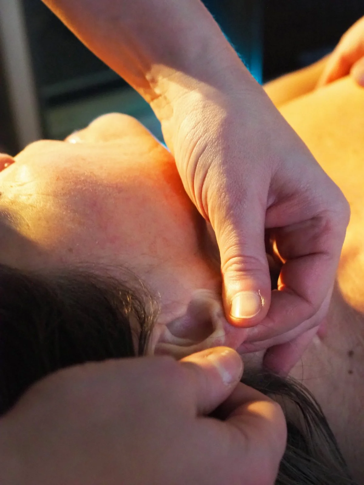 Henkilö antaa hierontaa tai akupunktiota niskalle ja pään alueelle, kädet toimivat hoitotilanteessa.