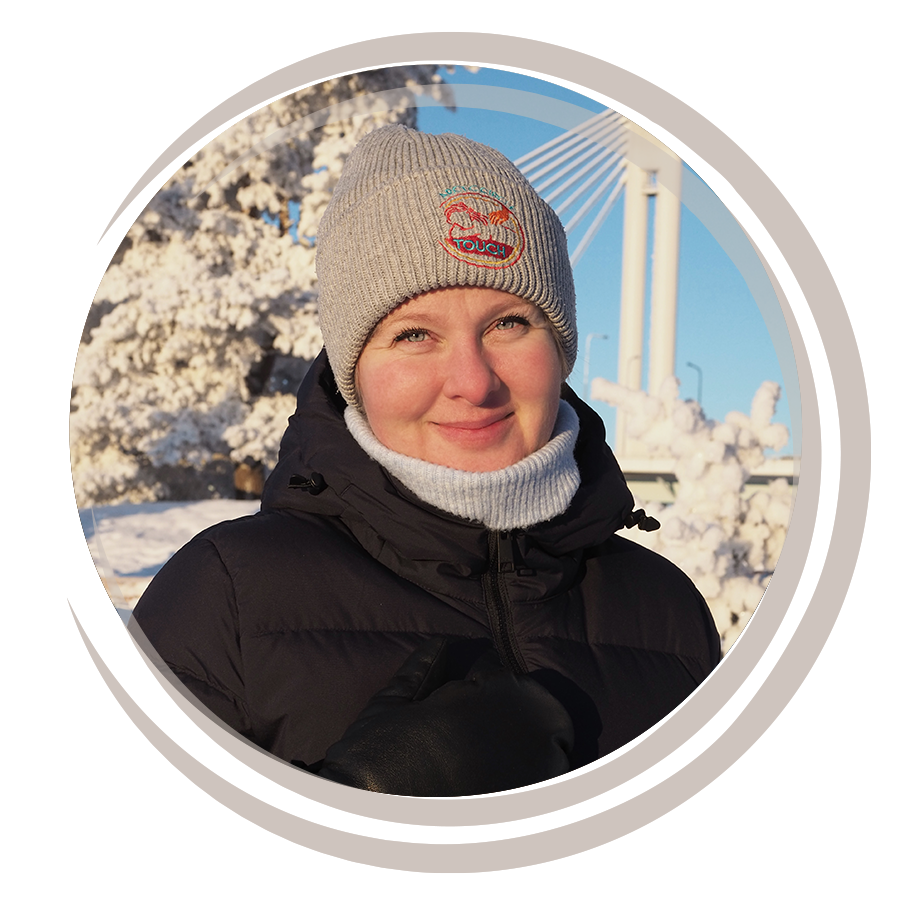 Nuori nainen talviviimeisellä säällä, pipo ja takki, lumimaisema ja silta taustalla.