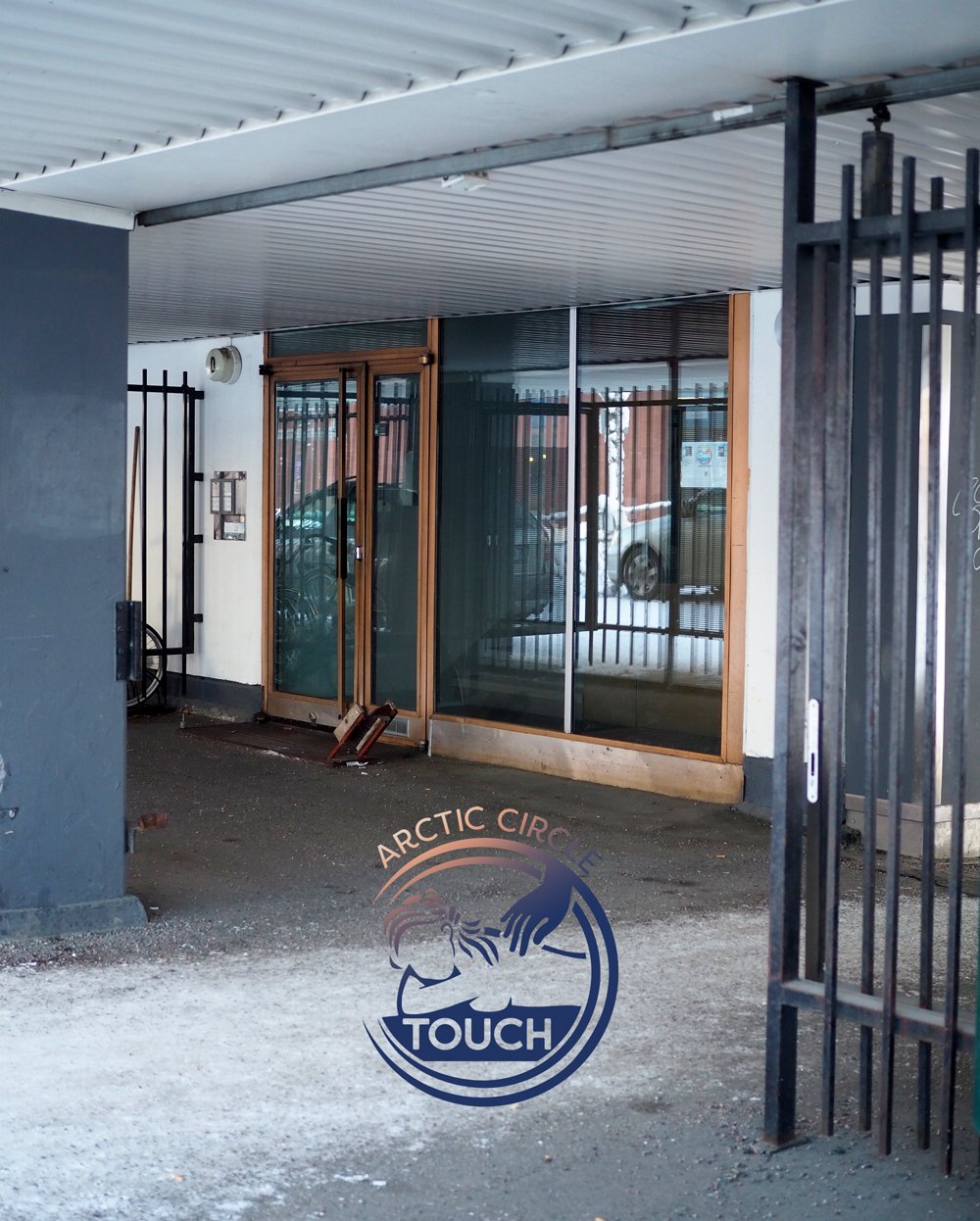 Kuvassa arktisen piirin kuvia ja teksti 'TOUCH' lasin ovessa, ulkoa näkyy autoja ja buildingsa ympäristössä