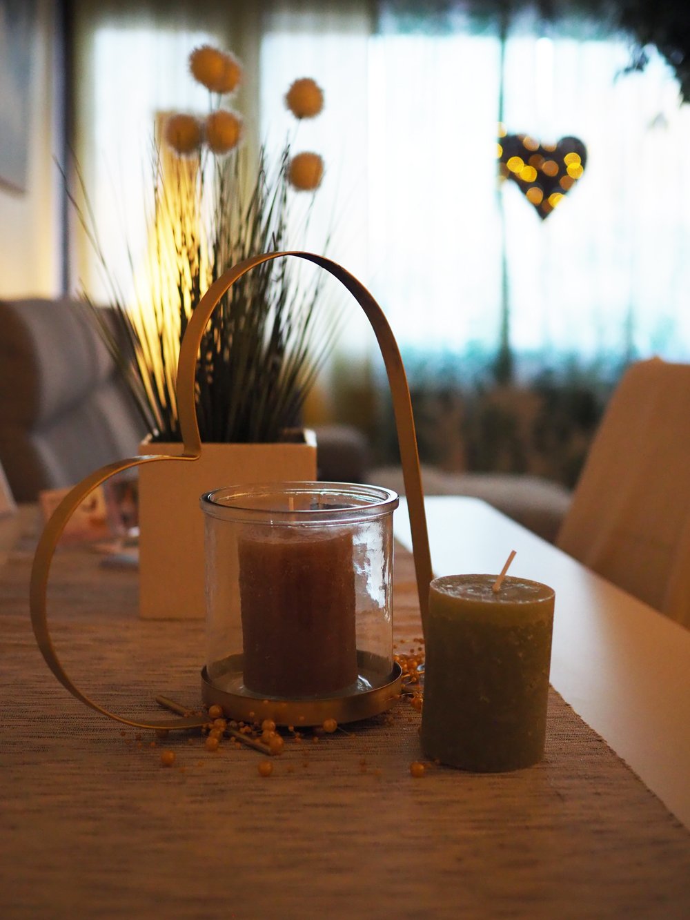 Yhden kynttilän, koristeellisen kukkakimpun ja sydänmuotoisen valaisimen sisustus.