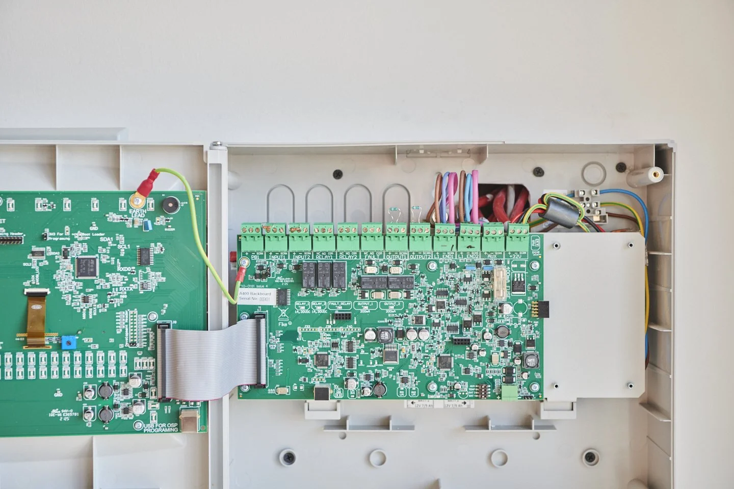Inside view of an electronic control panel with circuit boards, wiring, and electronic components.