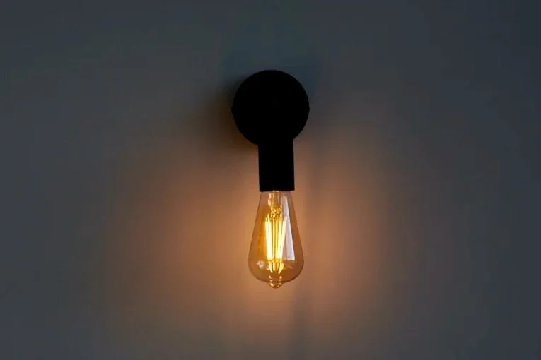 A wall-mounted light fixture with an exposed Edison-style lightbulb casting a warm glow.