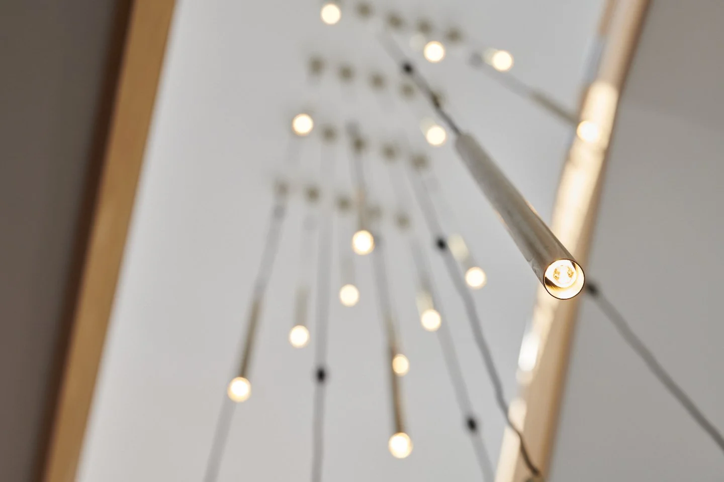 Close-up view of a modern chandelier with multiple small lights attached to thin black rods, seen from below against a white ceiling.