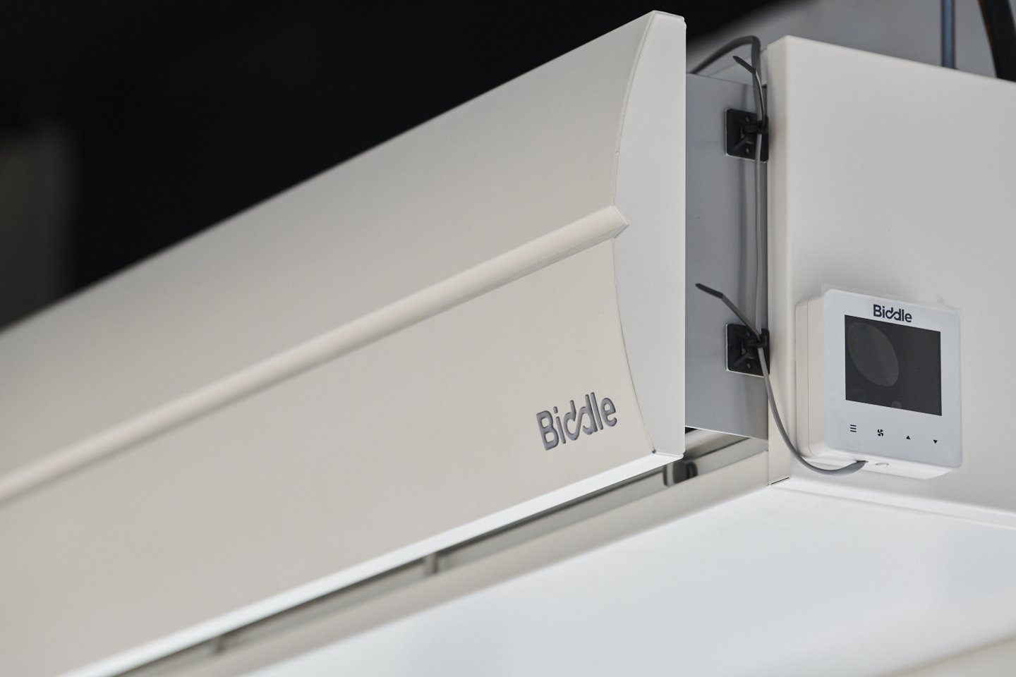 Close-up of a white Biddle fire alarm control panel and a separate white digital display mounted on a wall.