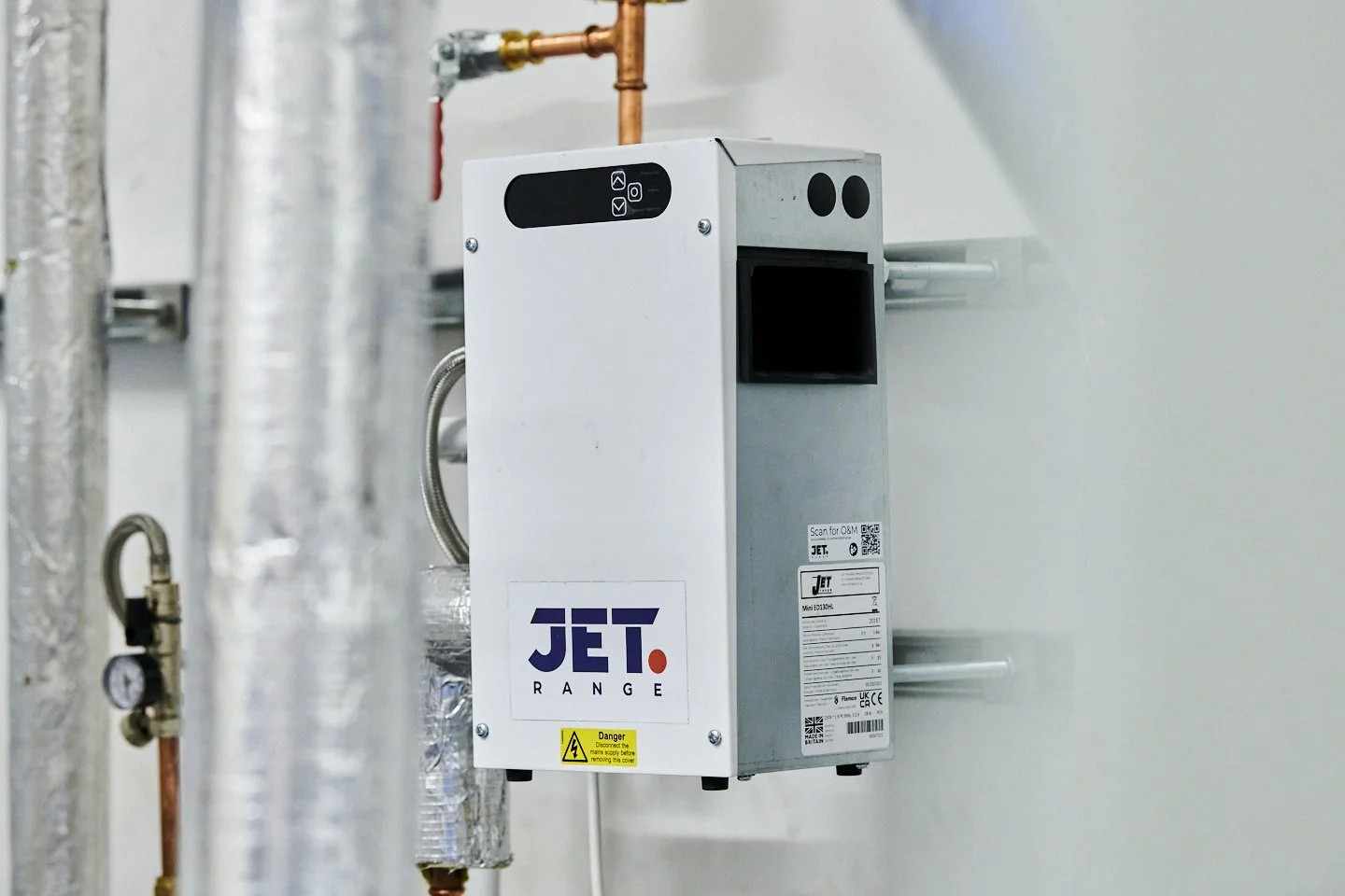 Industrial equipment labeled 'JET RANGE' with warning sign, pipes, and gauges in the background.