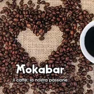 Coffee beans arranged in the shape of a heart on burlap with a cup of coffee and the text 'Mokabar, il caffè, la nostra passione'.