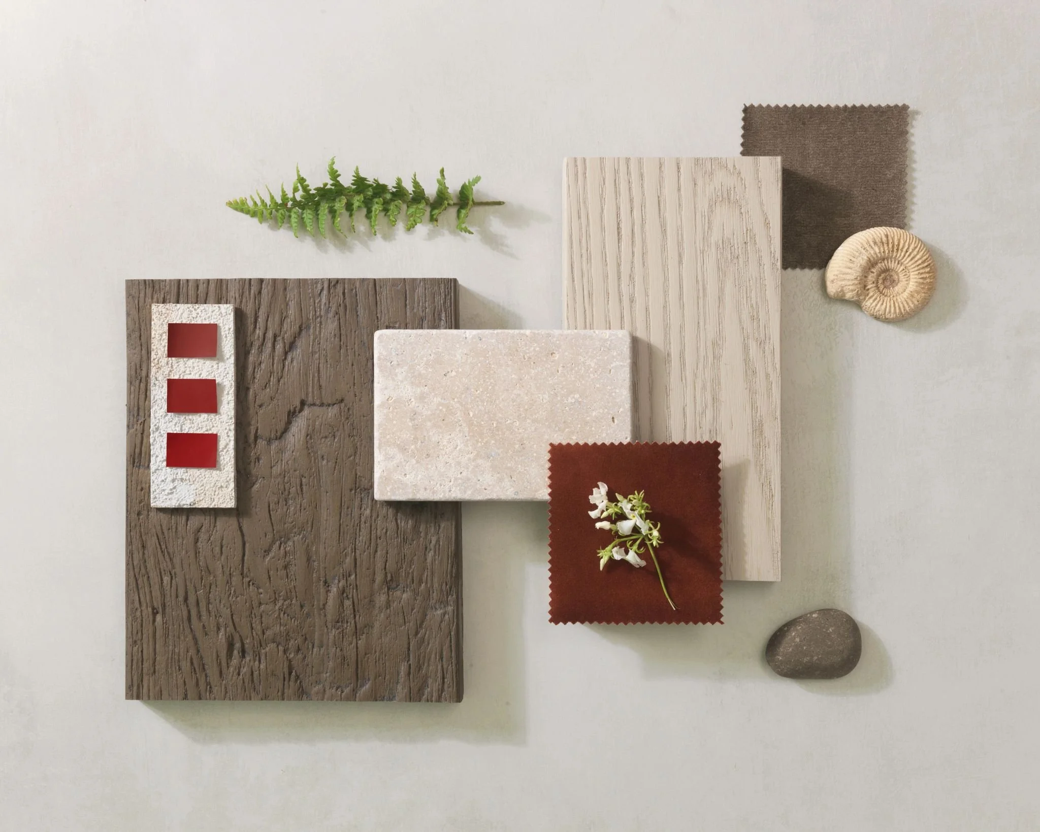 A flat lay of various material samples including wood, fabric, stone, and plant elements arranged on a light background.