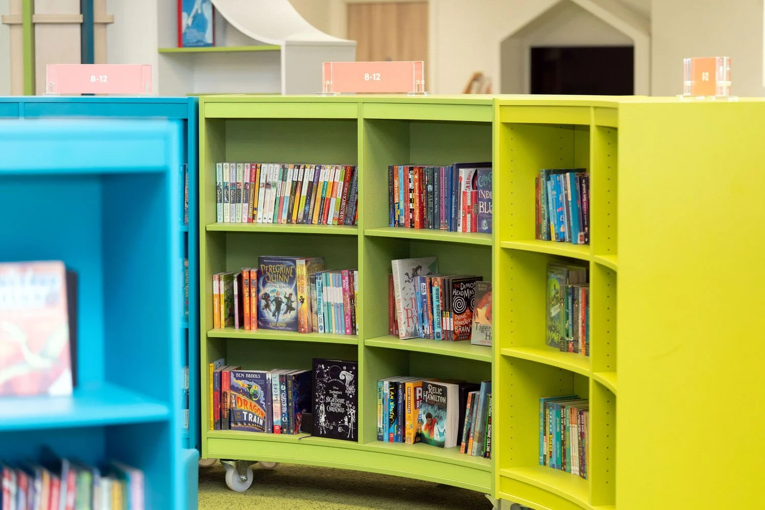 Bright coloured bookshelves filled with childrens books, inside the children's library at Y Storfa in Swansea.